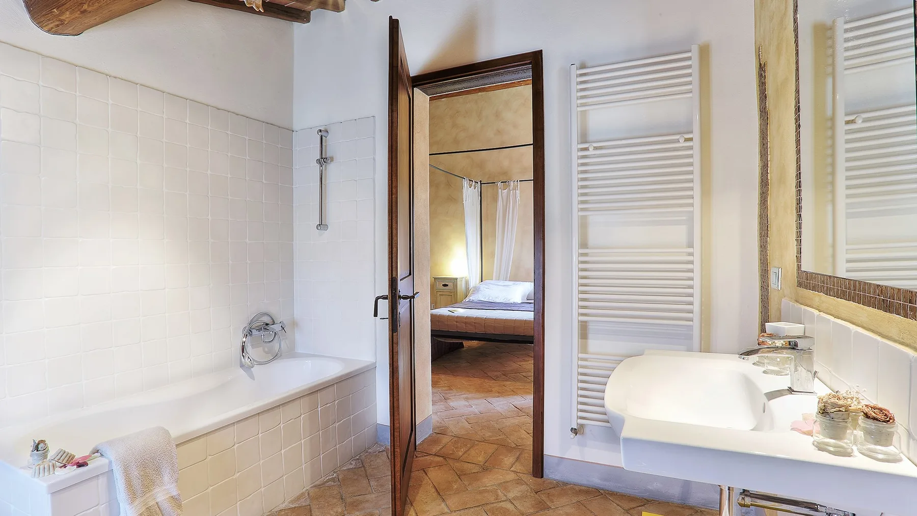A bathroom with a bathtub, sink, and tall white towel radiator.