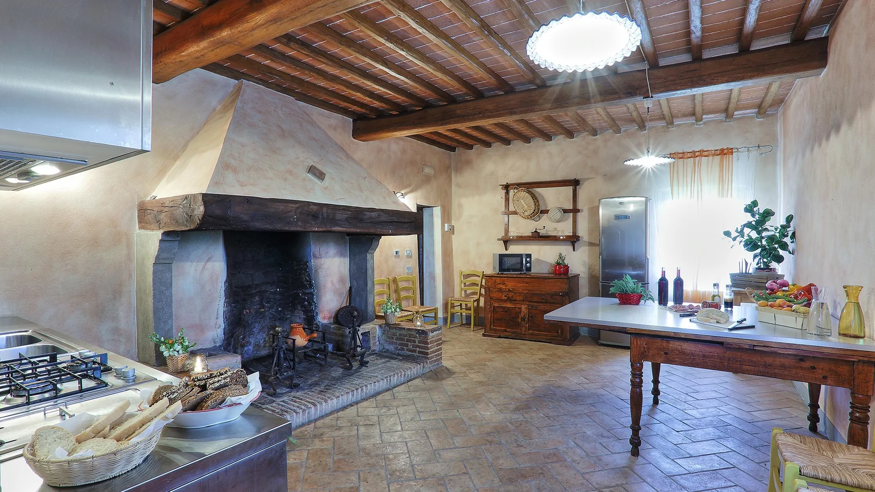 A rustic kitchen and dining area with a large fireplace and a wooden table.
