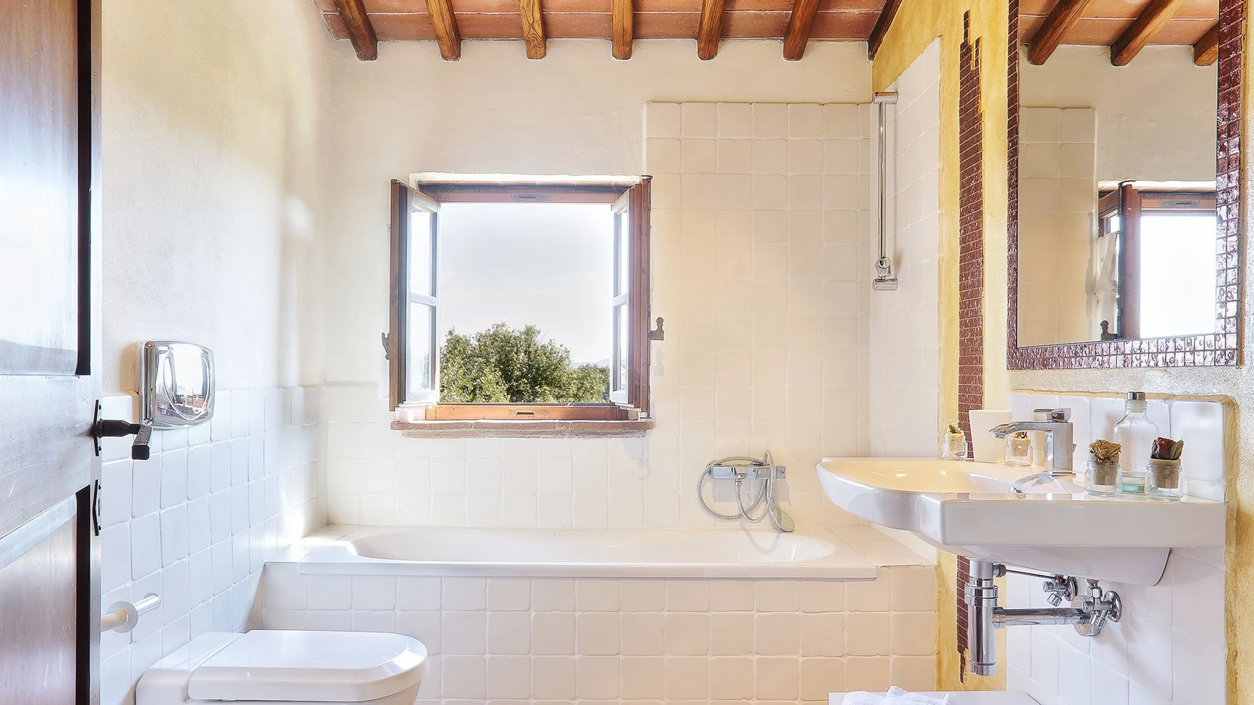 A tiled bathroom with a bathtub, sink, and window.
