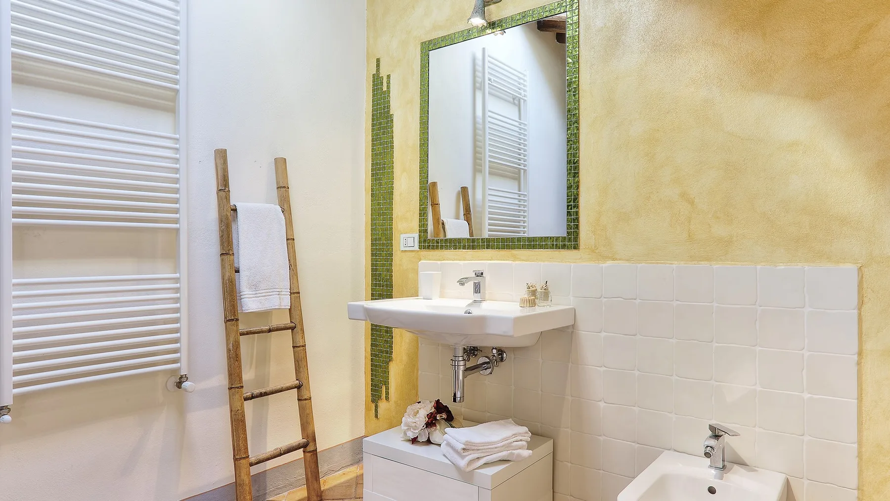 A bathroom with a sink, mirror, and white wall tiles.