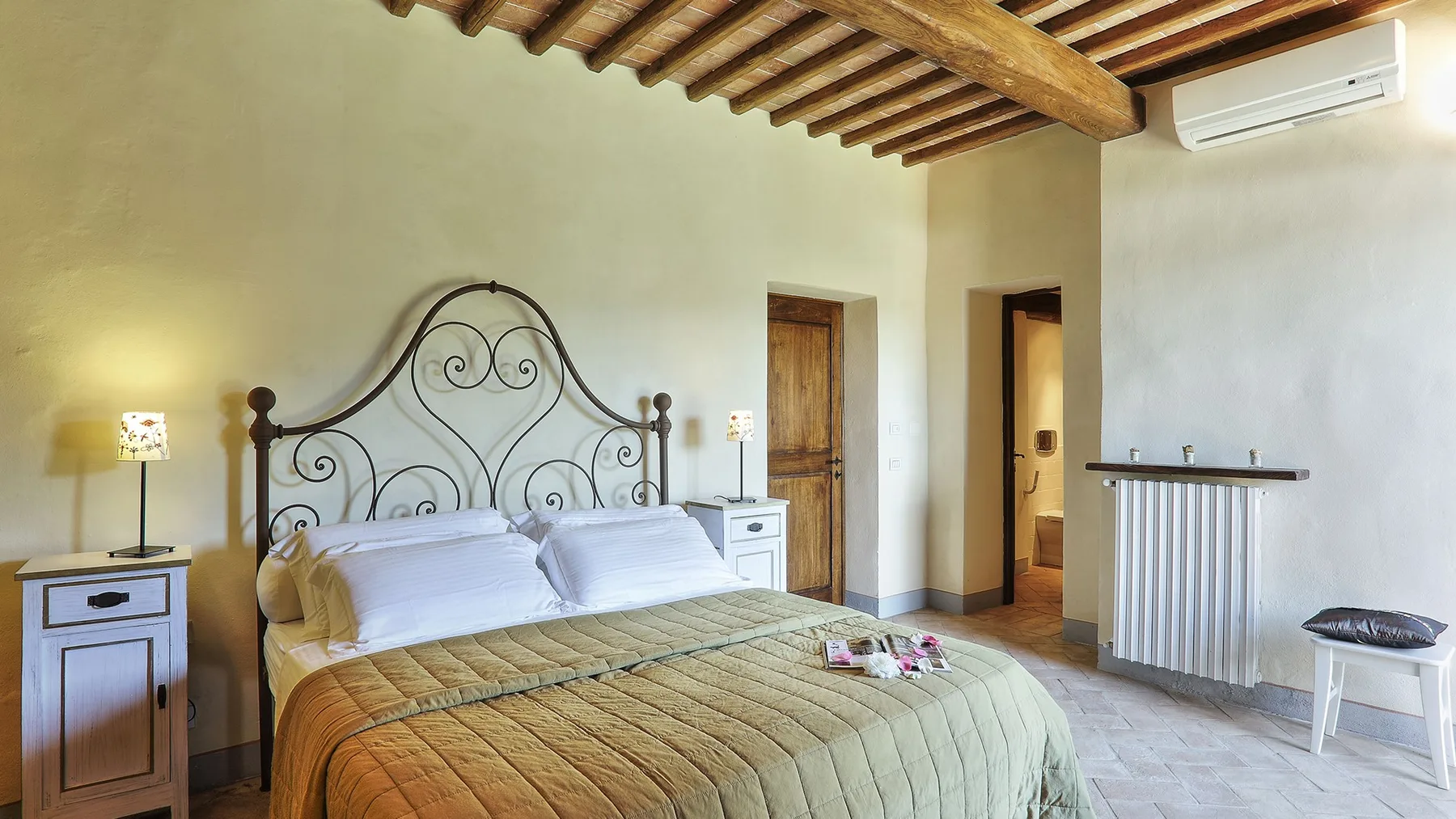 A bedroom with a metal bed, bedside tables, and exposed wooden ceiling beams.