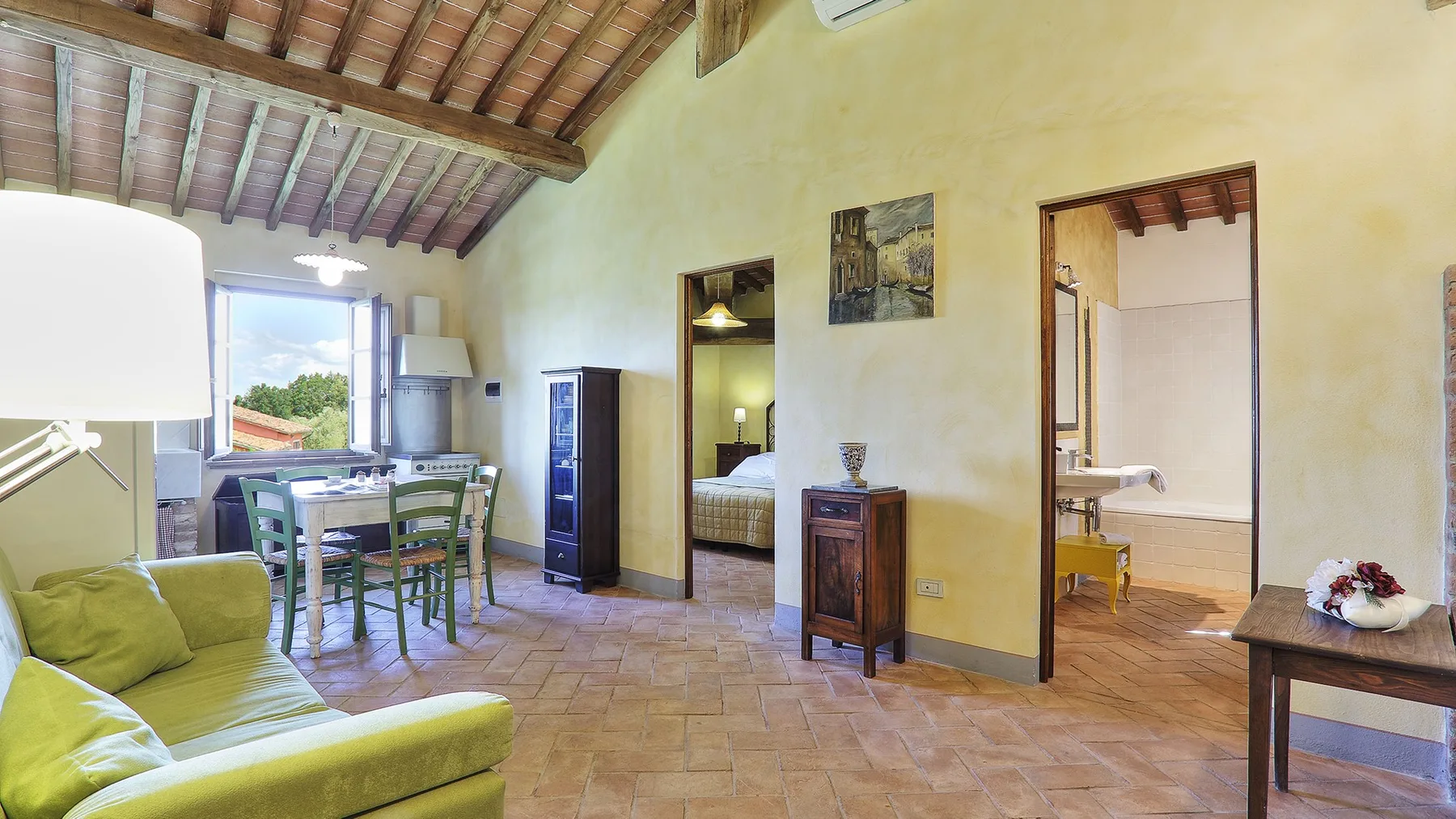 A rustic living and dining area opens onto a bedroom and bathroom.