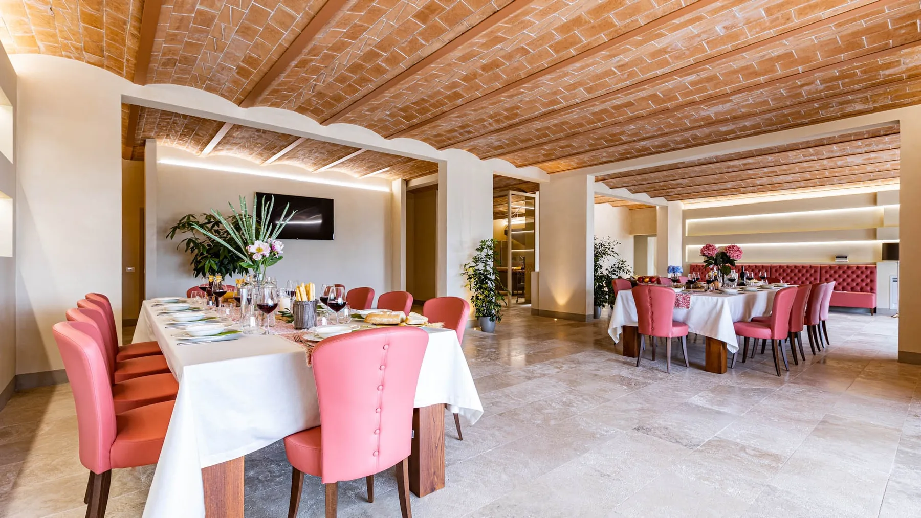 A dining room with tables set with white linens and pink seating.