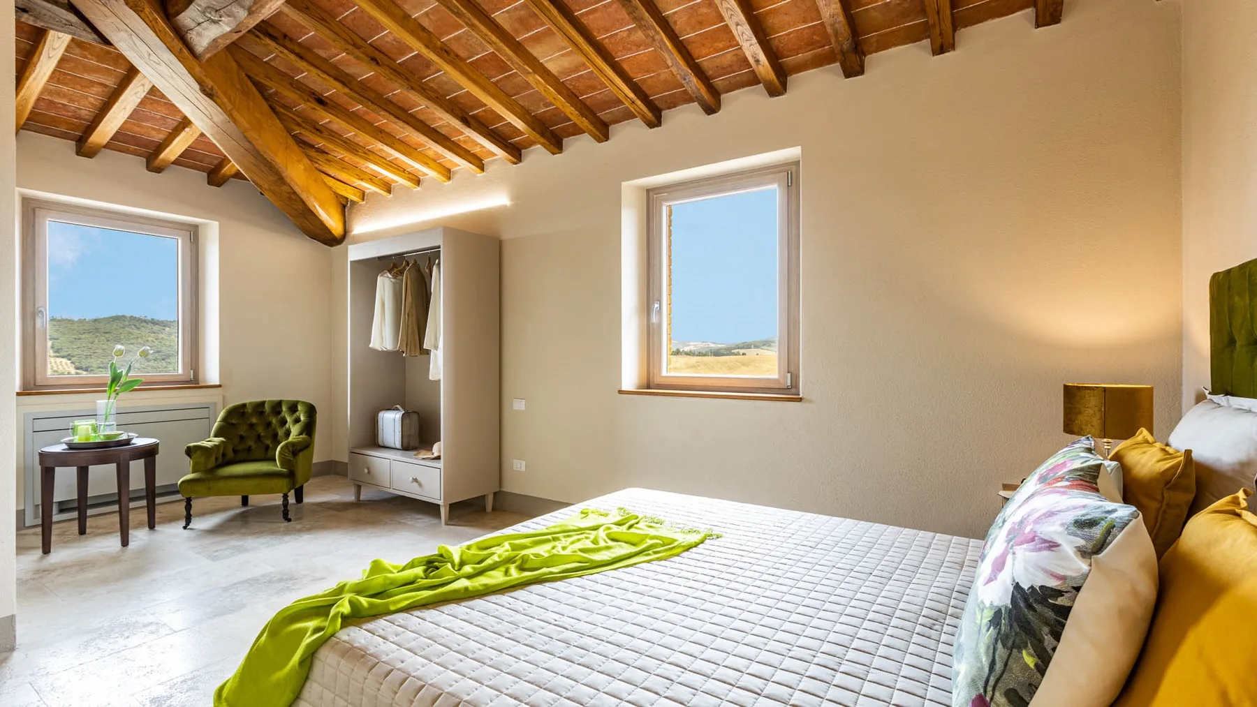 A bright bedroom with a bed beneath exposed wooden ceiling beams.