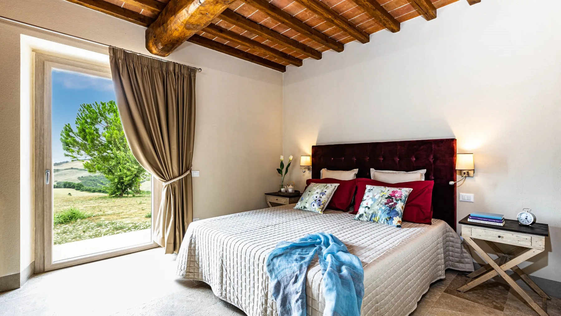 A bedroom with a large bed beneath exposed wooden ceiling beams.