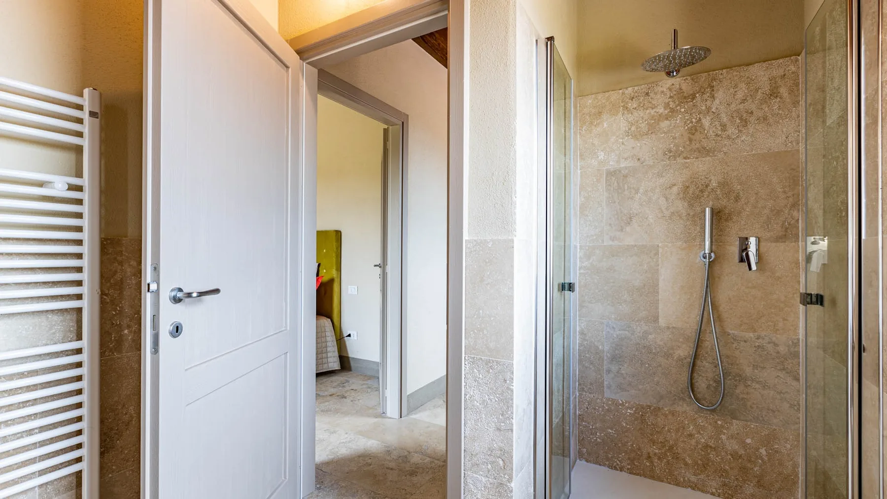 A bathroom with a glass shower and an open doorway.