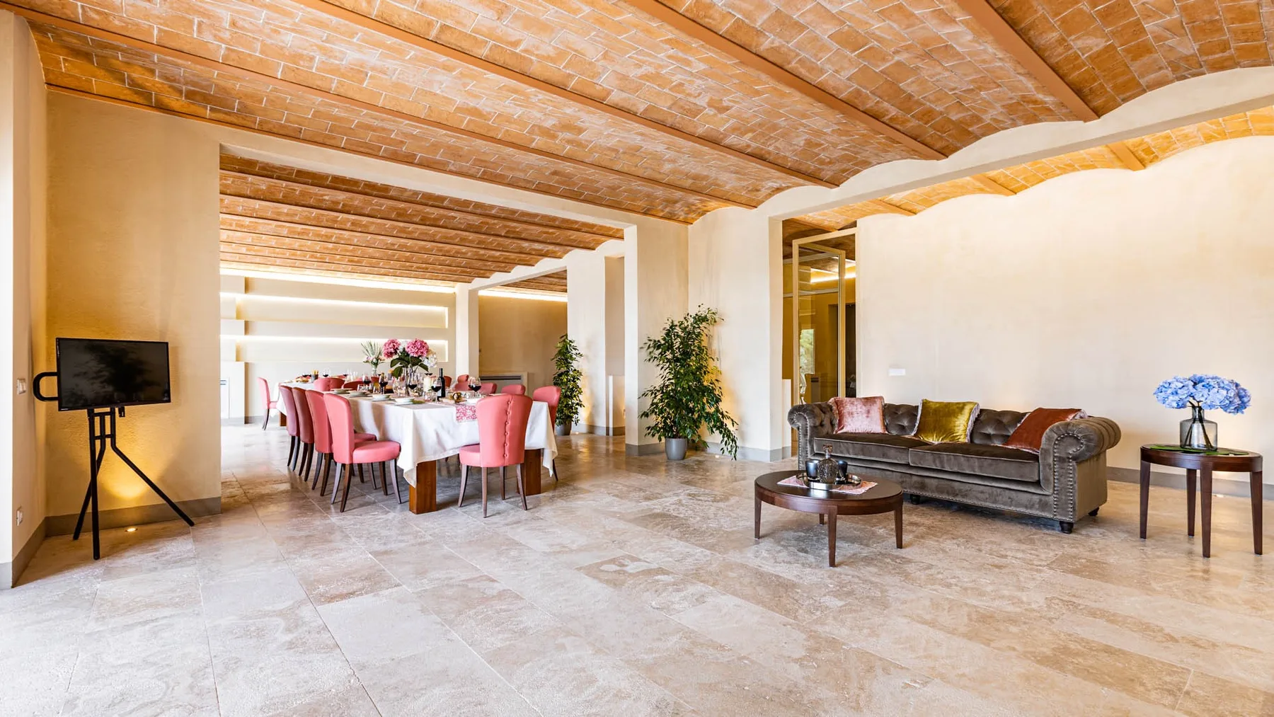 A spacious living and dining area with seating, a dining table, and a vaulted brick ceiling.