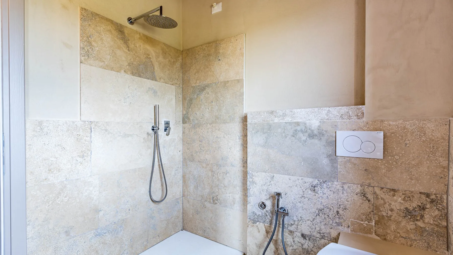 A tiled bathroom shower area with a wall-mounted showerhead and fixtures.