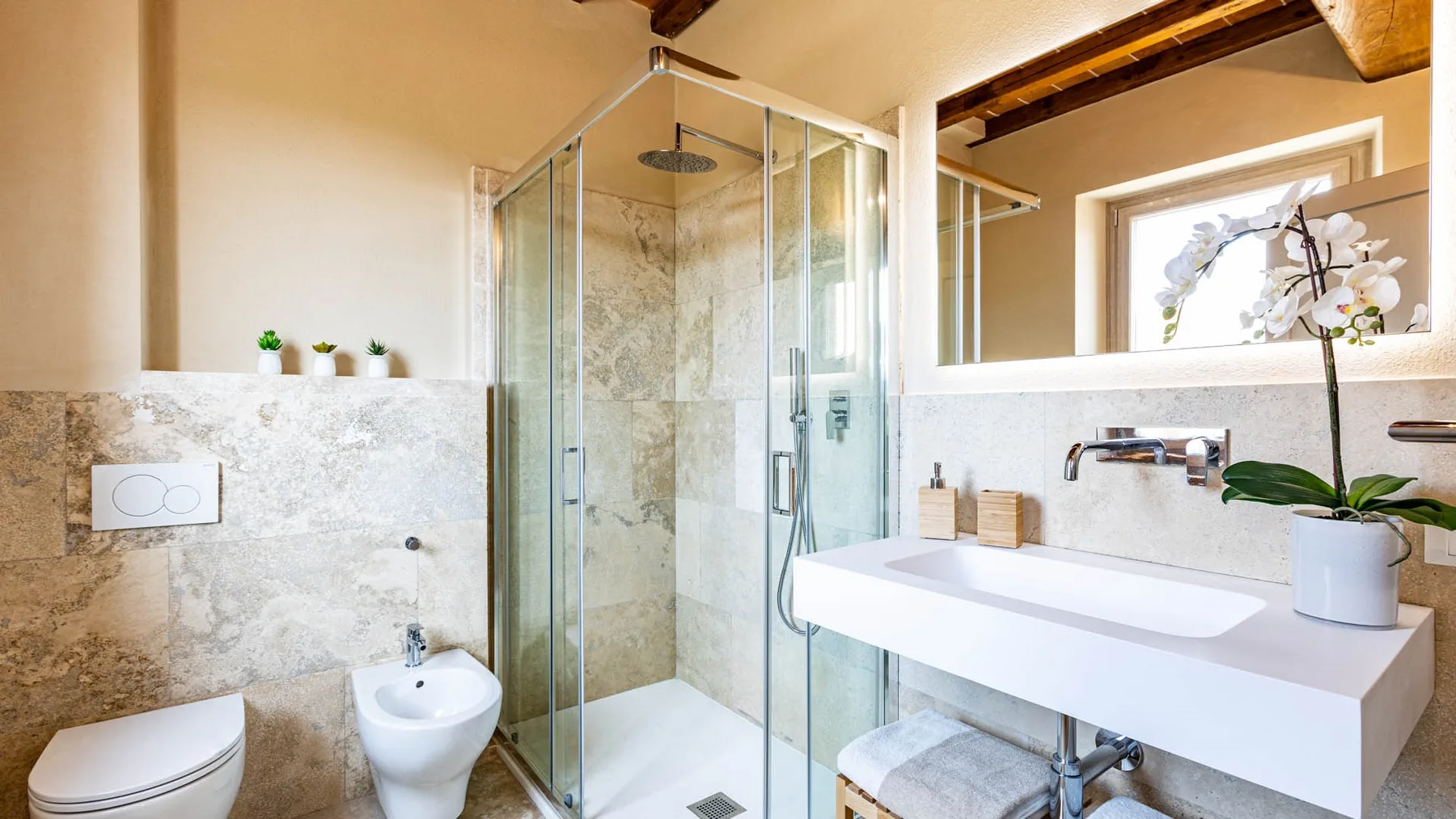 A bright bathroom with a glass shower and a wide sink counter.