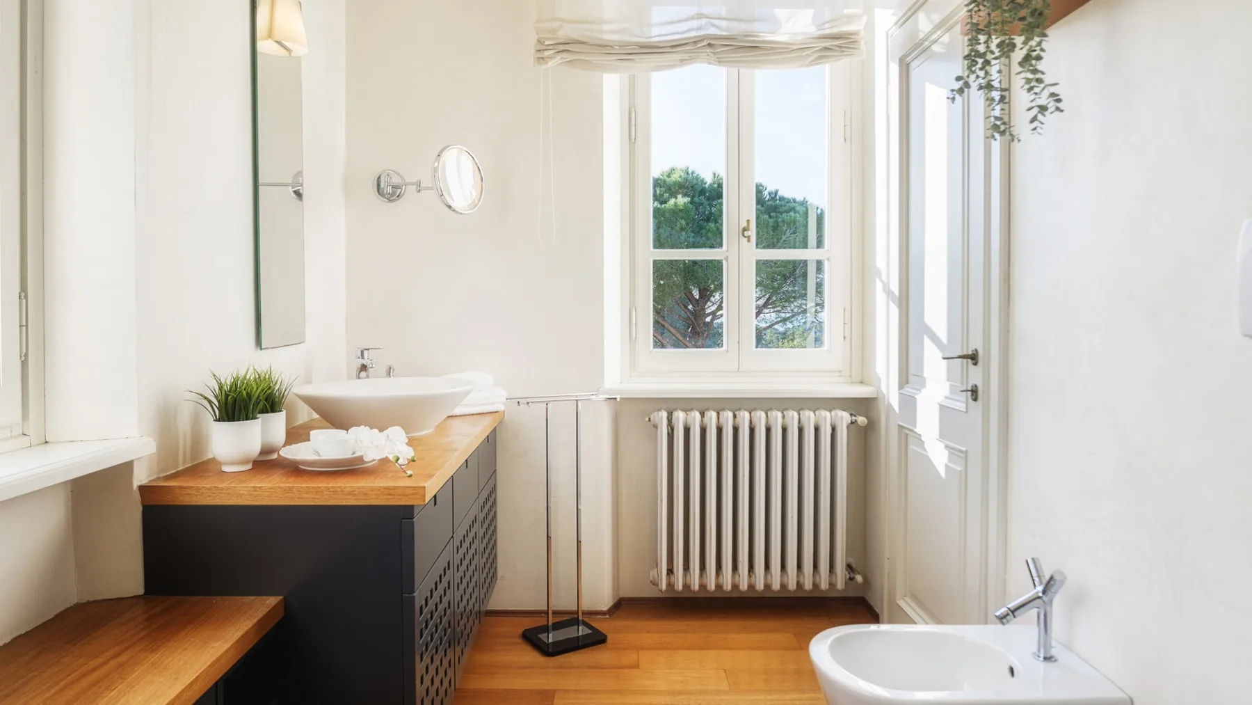 Un baño luminoso con tocador de madera, bañera y ventanas grandes.