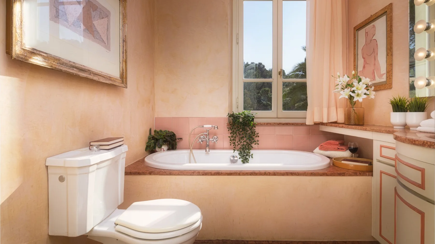 Un baño con bañera, inodoro y una ventana con vistas a la vegetación.