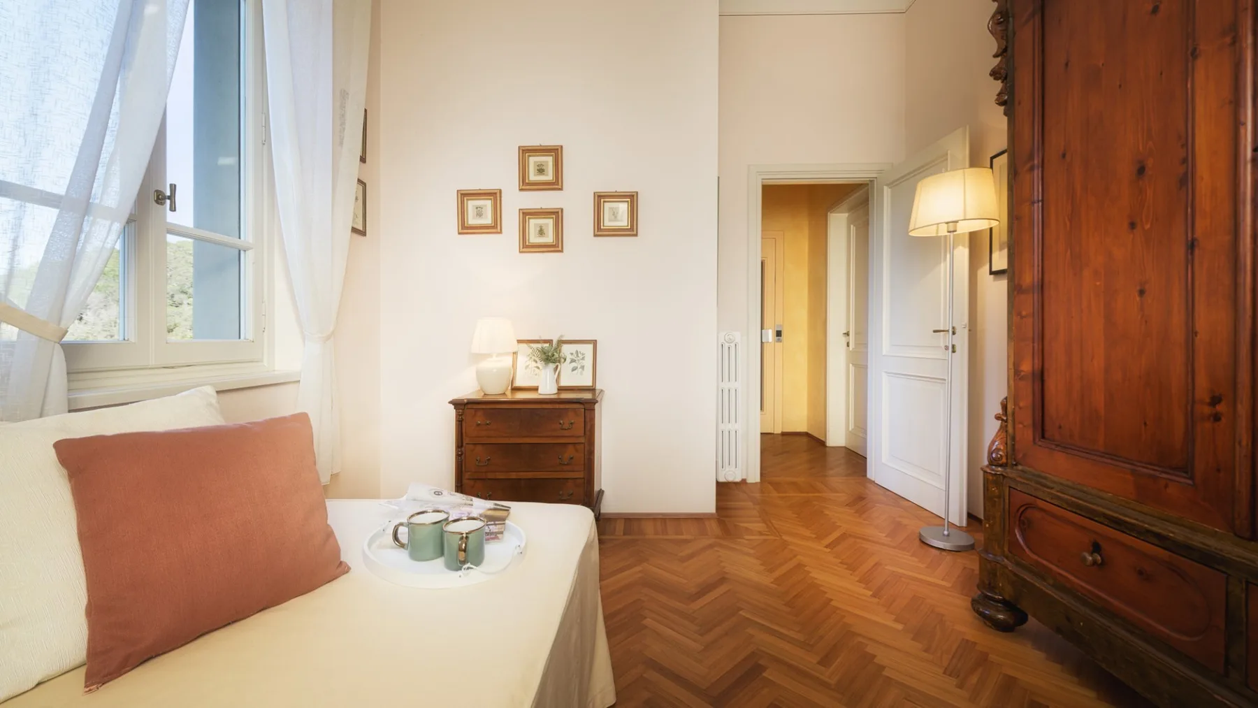 Una luminosa sala de estar con una cama, un armario de madera y una puerta abierta.