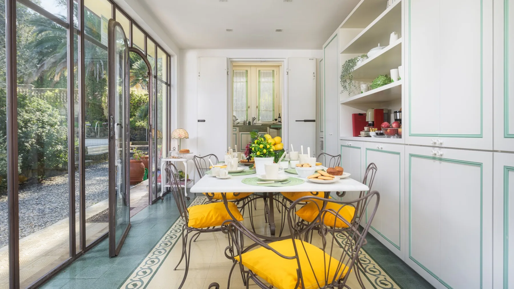 Un comedor luminoso con una mesa larga preparada junto a grandes ventanas.