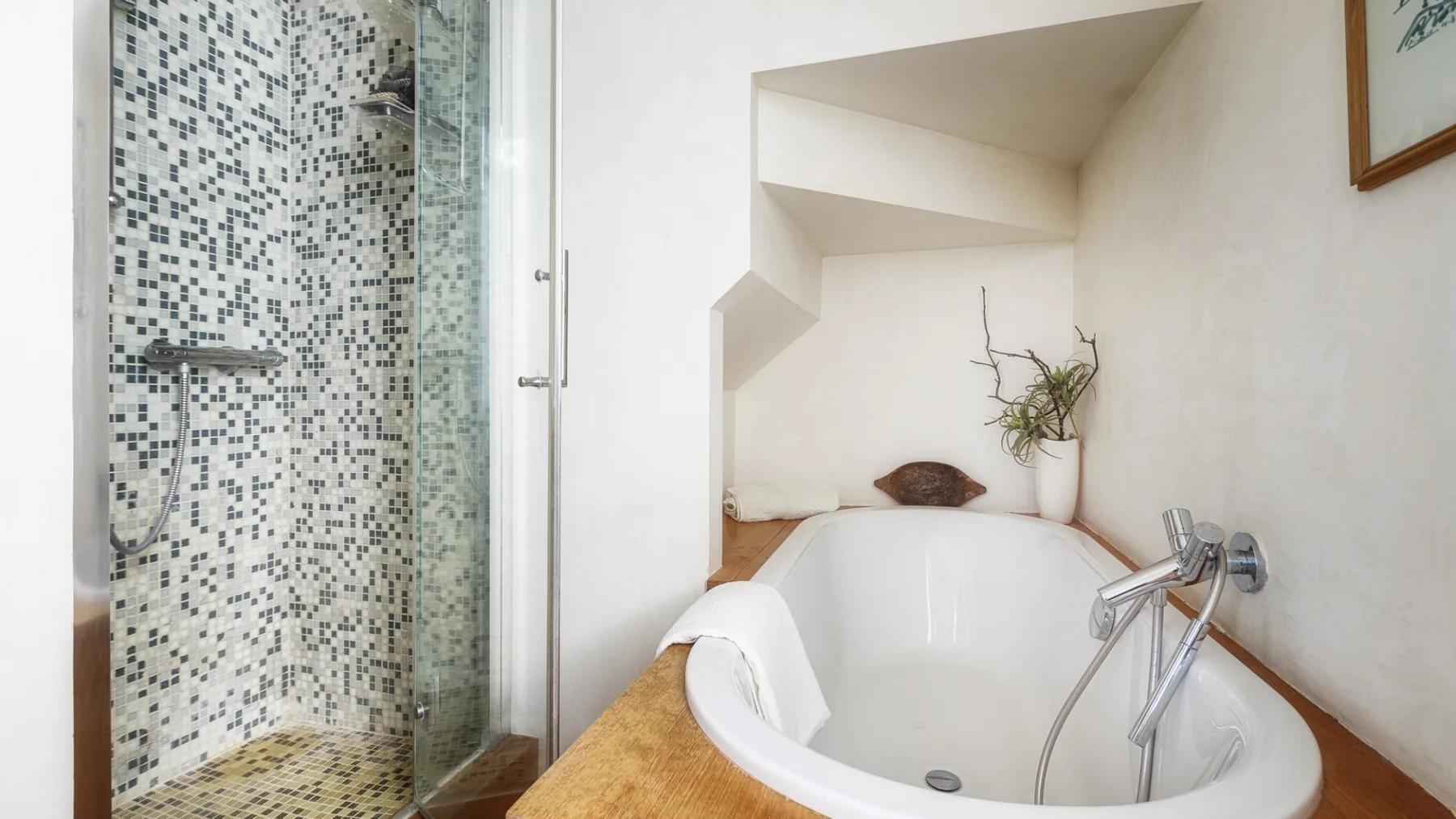 Un baño luminoso con una bañera junto a una ducha con azulejos.