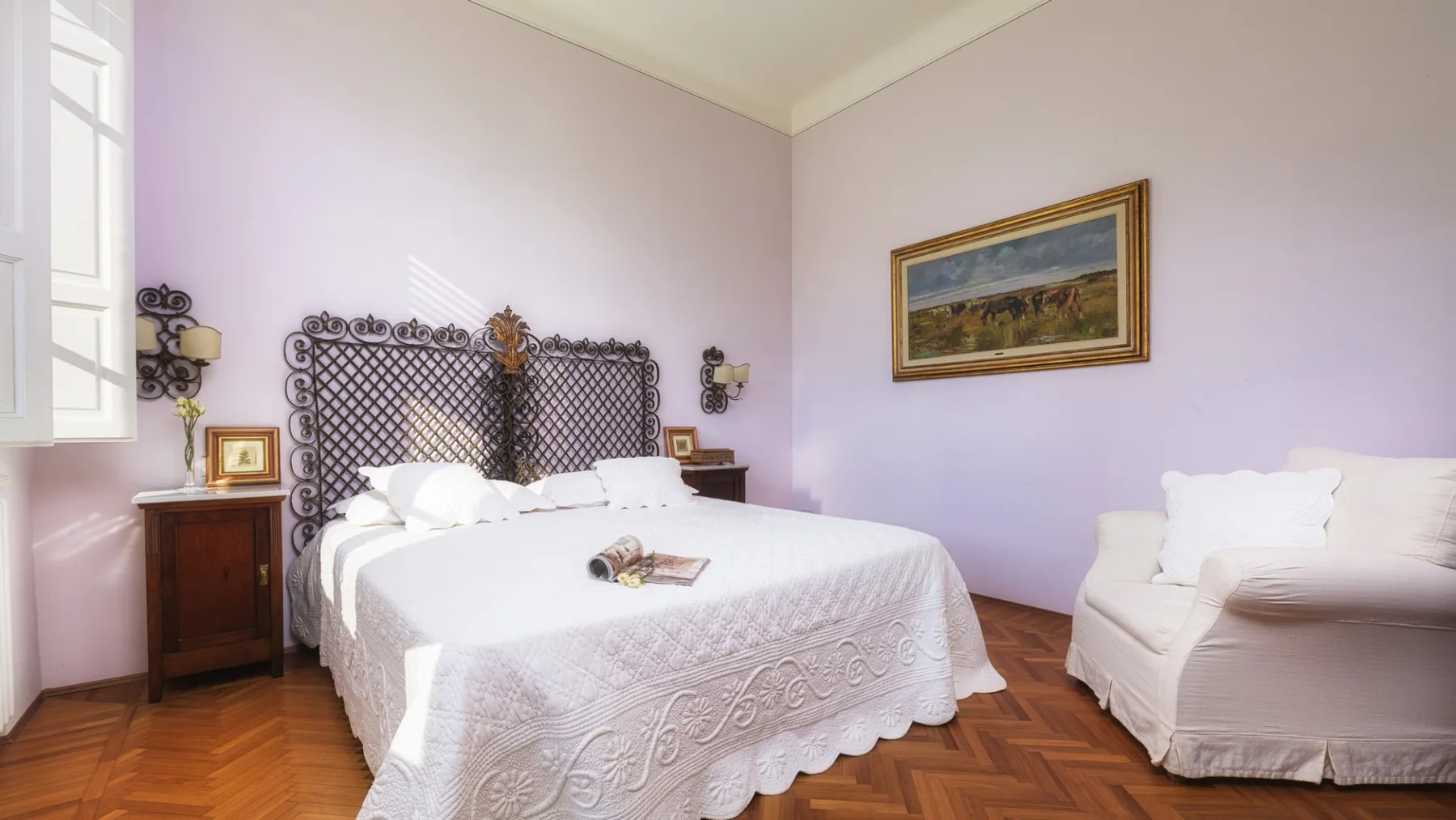 Un dormitorio con una cama blanca y un sillón tapizado al lado.