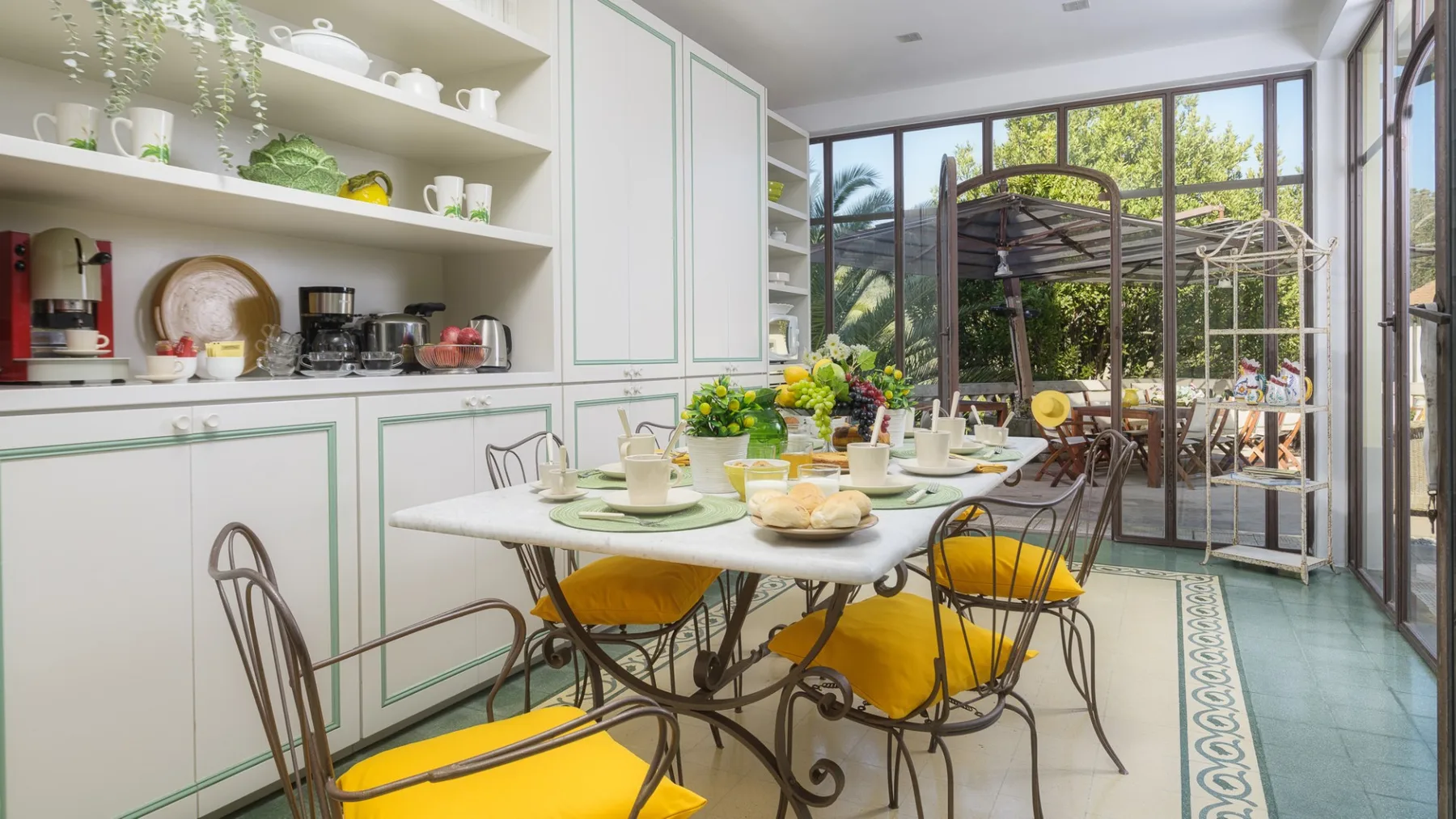 Un comedor luminoso con la mesa puesta junto a un gran ventanal con vistas a la vegetación.