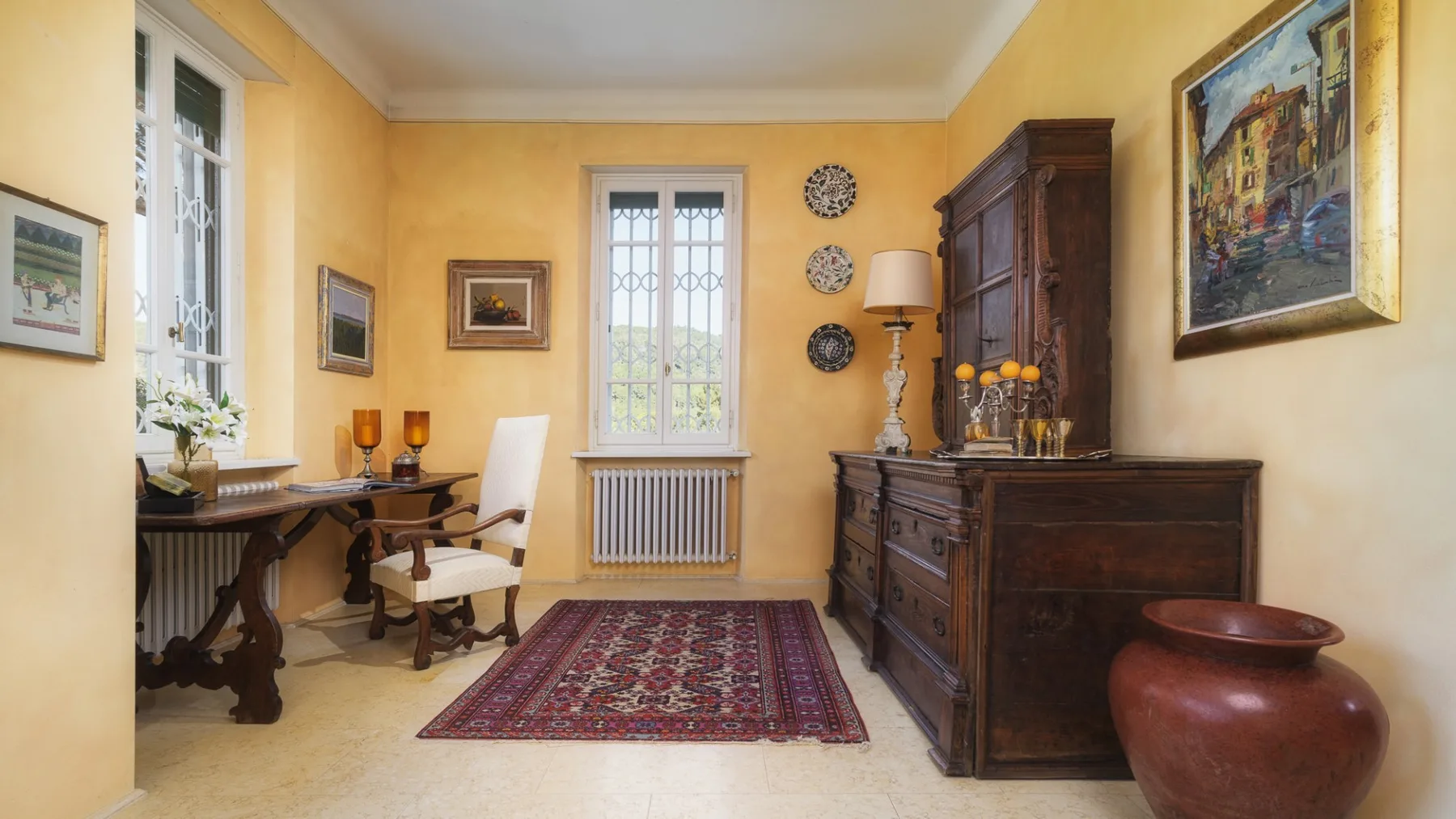 Una habitación de tonos cálidos con escritorio, mueble de madera y alfombra estampada.