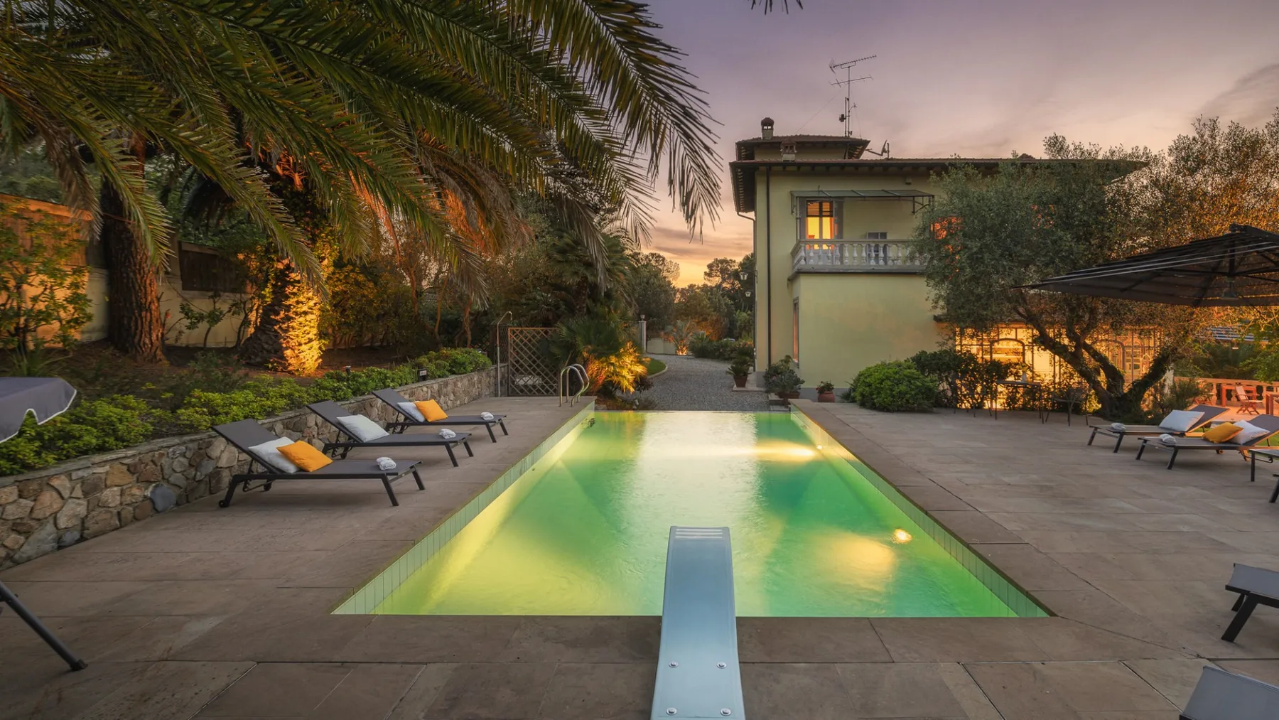 Una piscina al aire libre está rodeada de asientos y palmeras al anochecer.