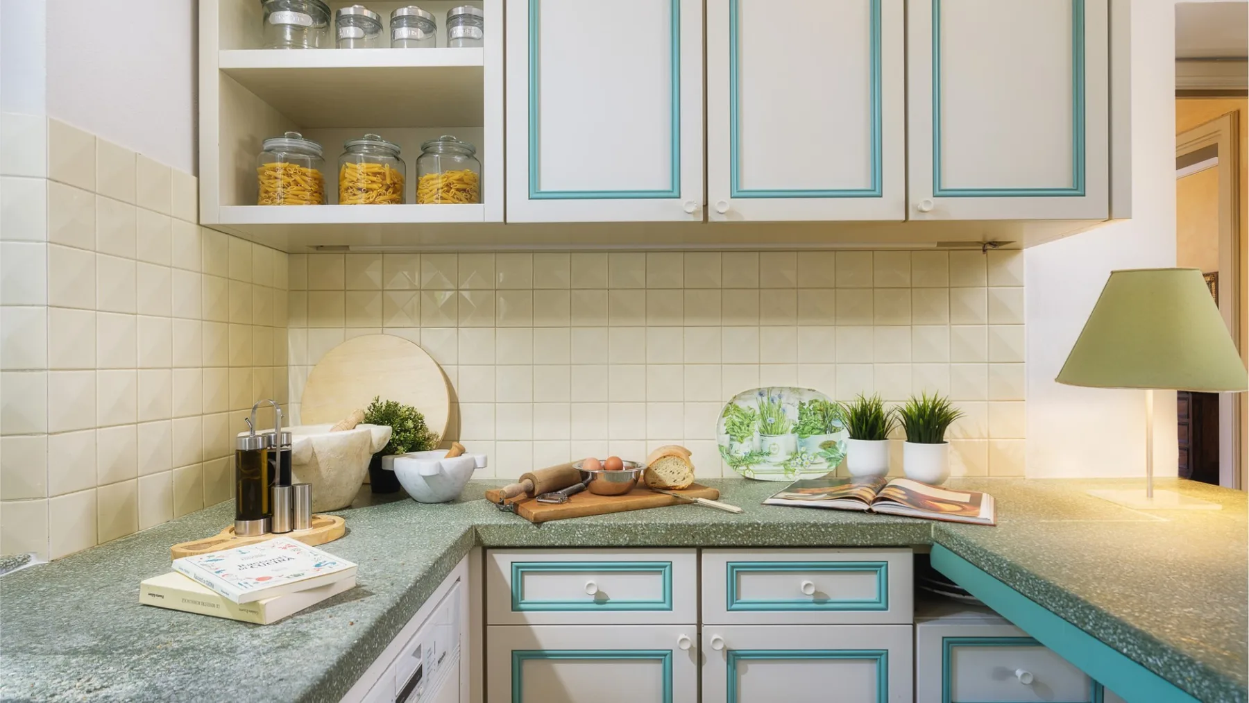 Una cocina con encimeras verdes y armarios de tonos claros.