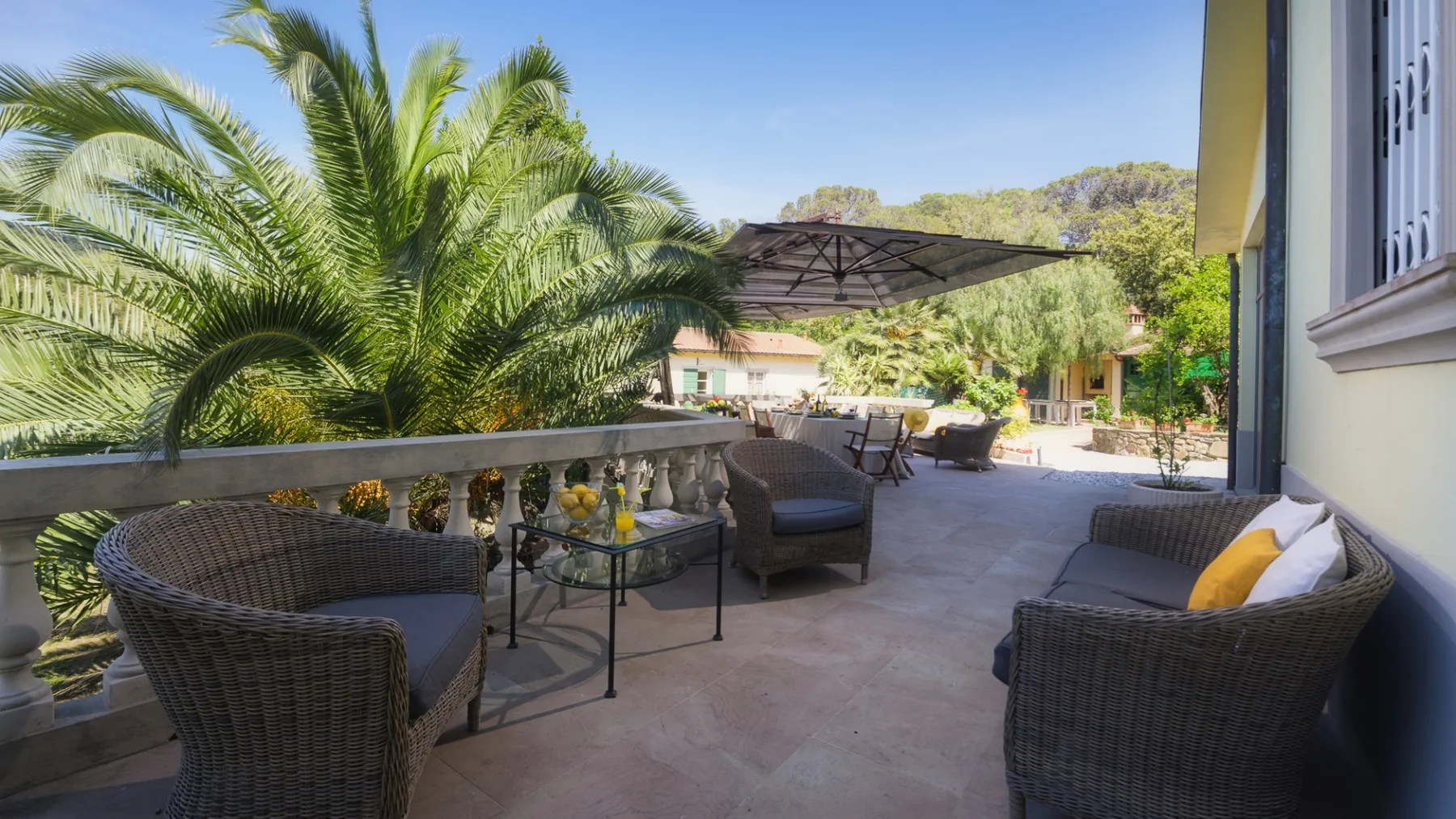 Un patio al aire libre con asientos de mimbre y vistas al jardín.