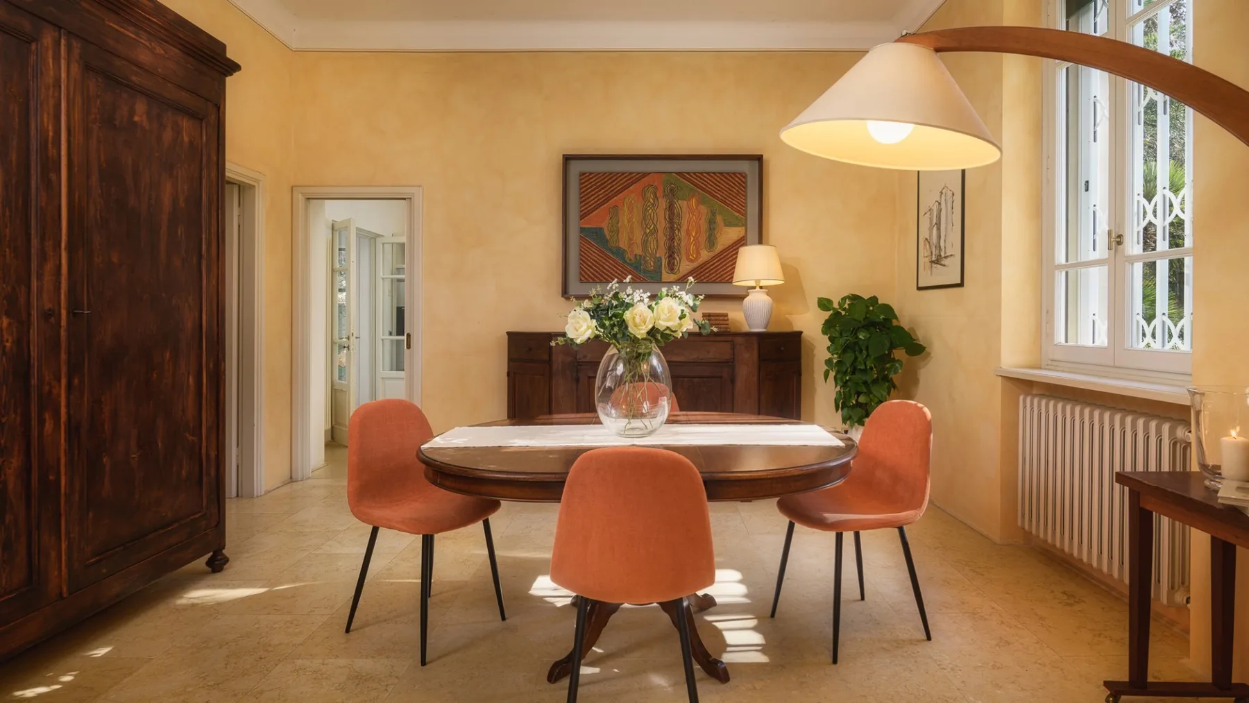 Comedor con una mesa redonda, asientos naranjas y una lámpara colgante grande.