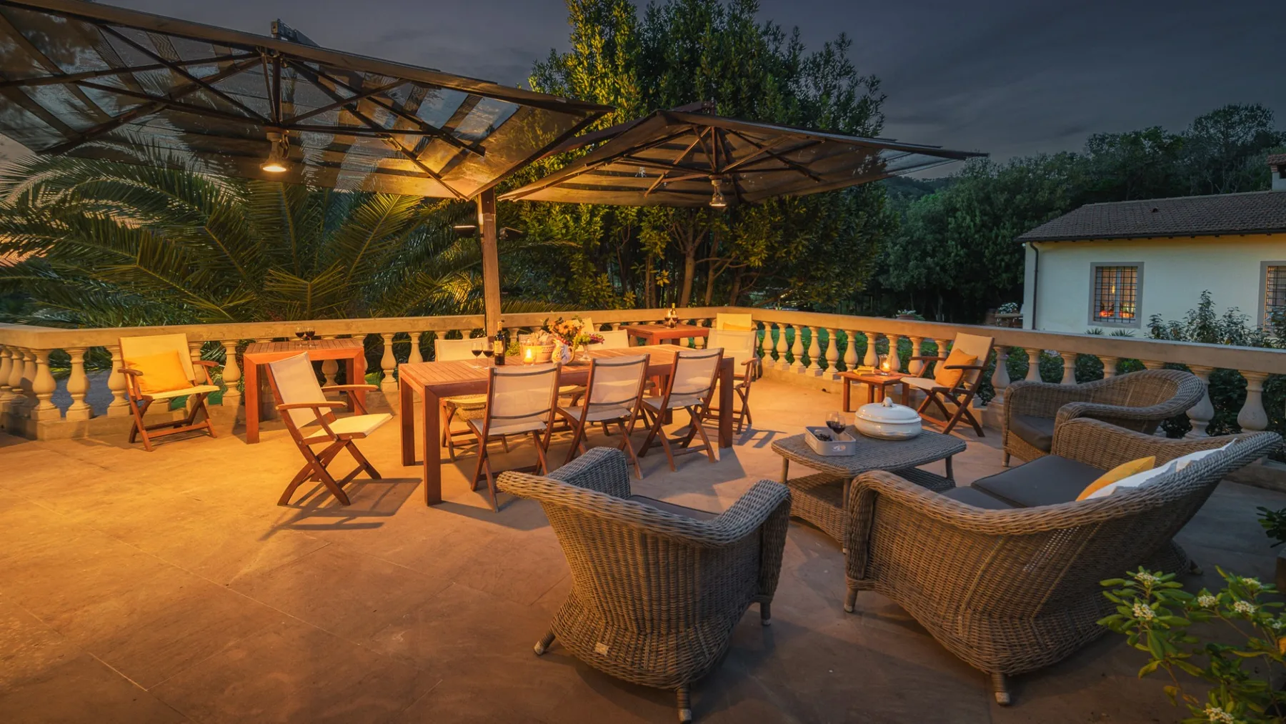 Un patio exterior cubierto con mesa de comedor y asientos de mimbre da a una balaustrada.