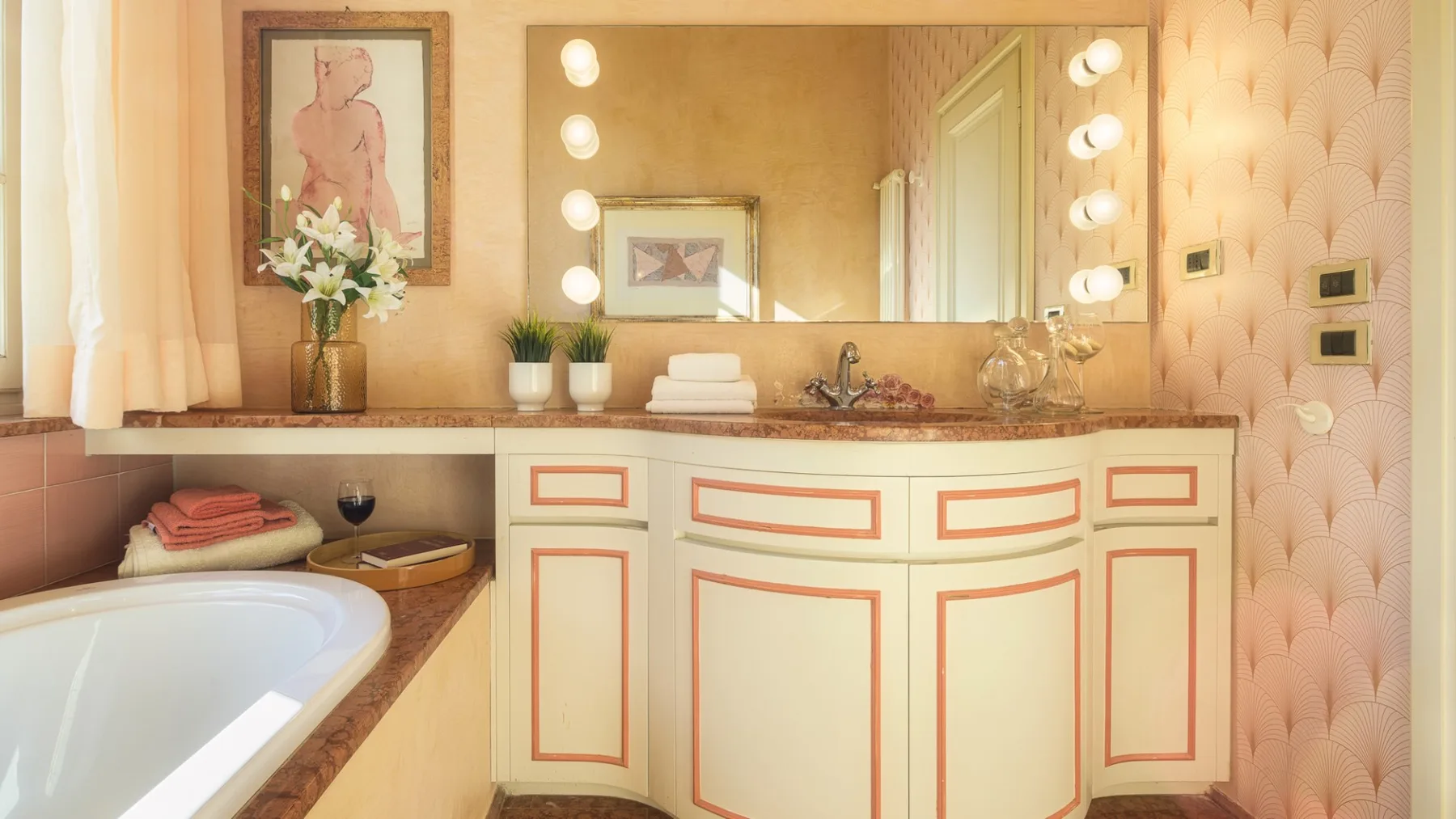Un tocador de baño con un espejo grande, bombillas iluminadas y una bañera.