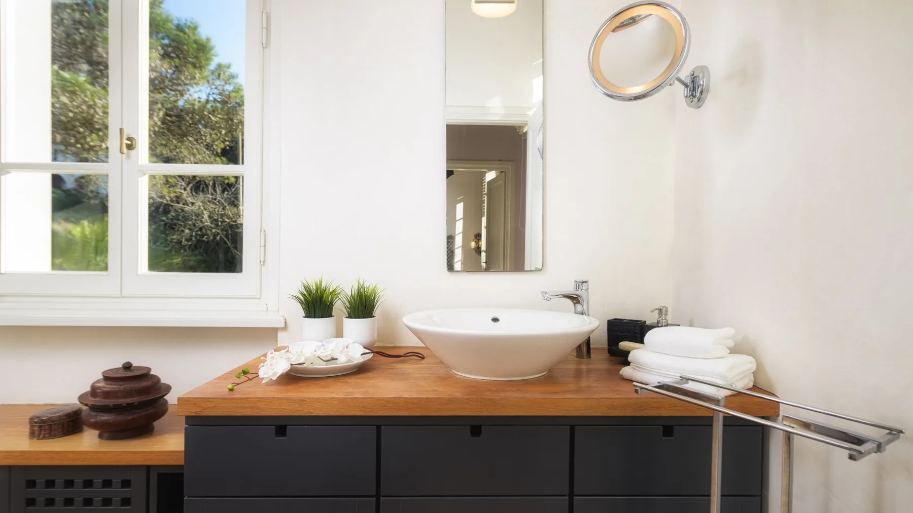 Un tocador de baño luminoso con un espejo amplio, lavabo blanco y toallas dobladas.
