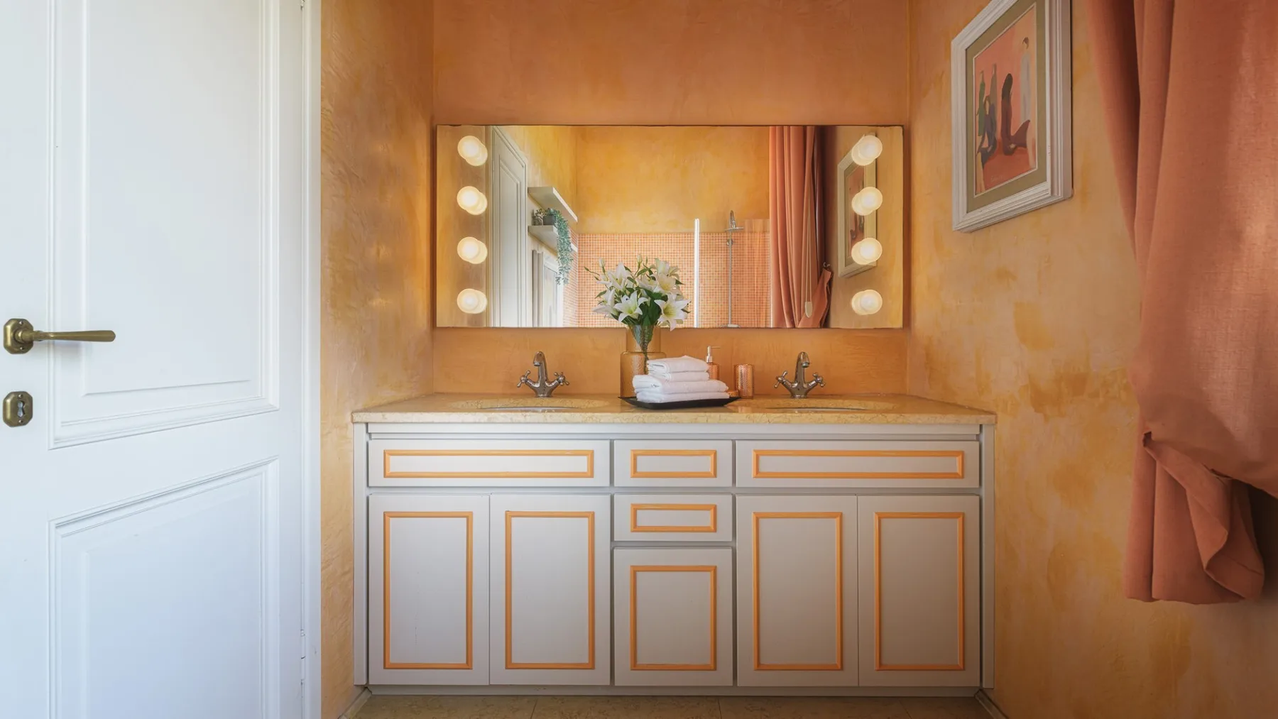 Un tocador de baño con un espejo amplio y un mueble blanco con paneles.