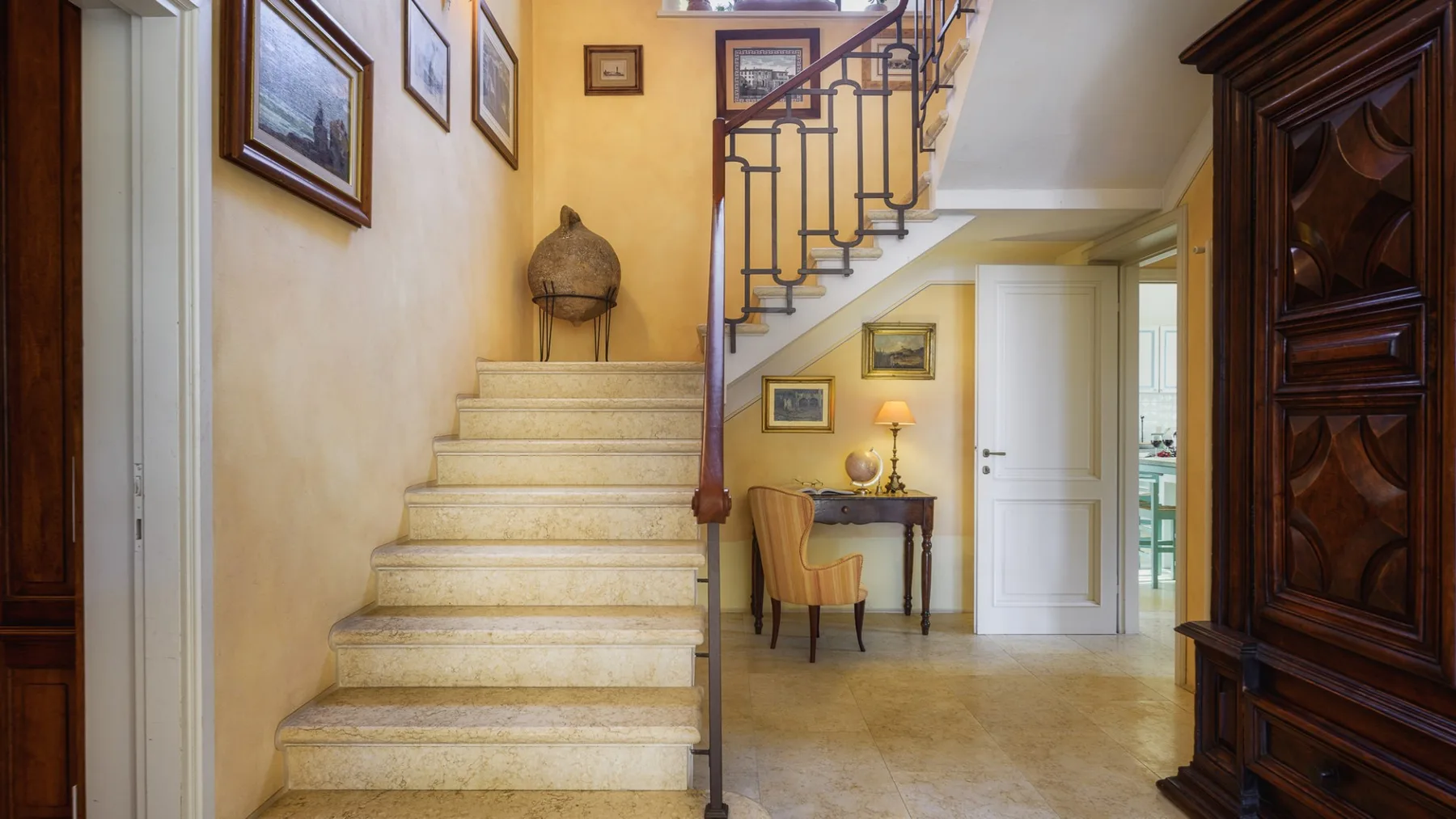 Una entrada interior luminosa presenta una escalera y una mesa pequeña.