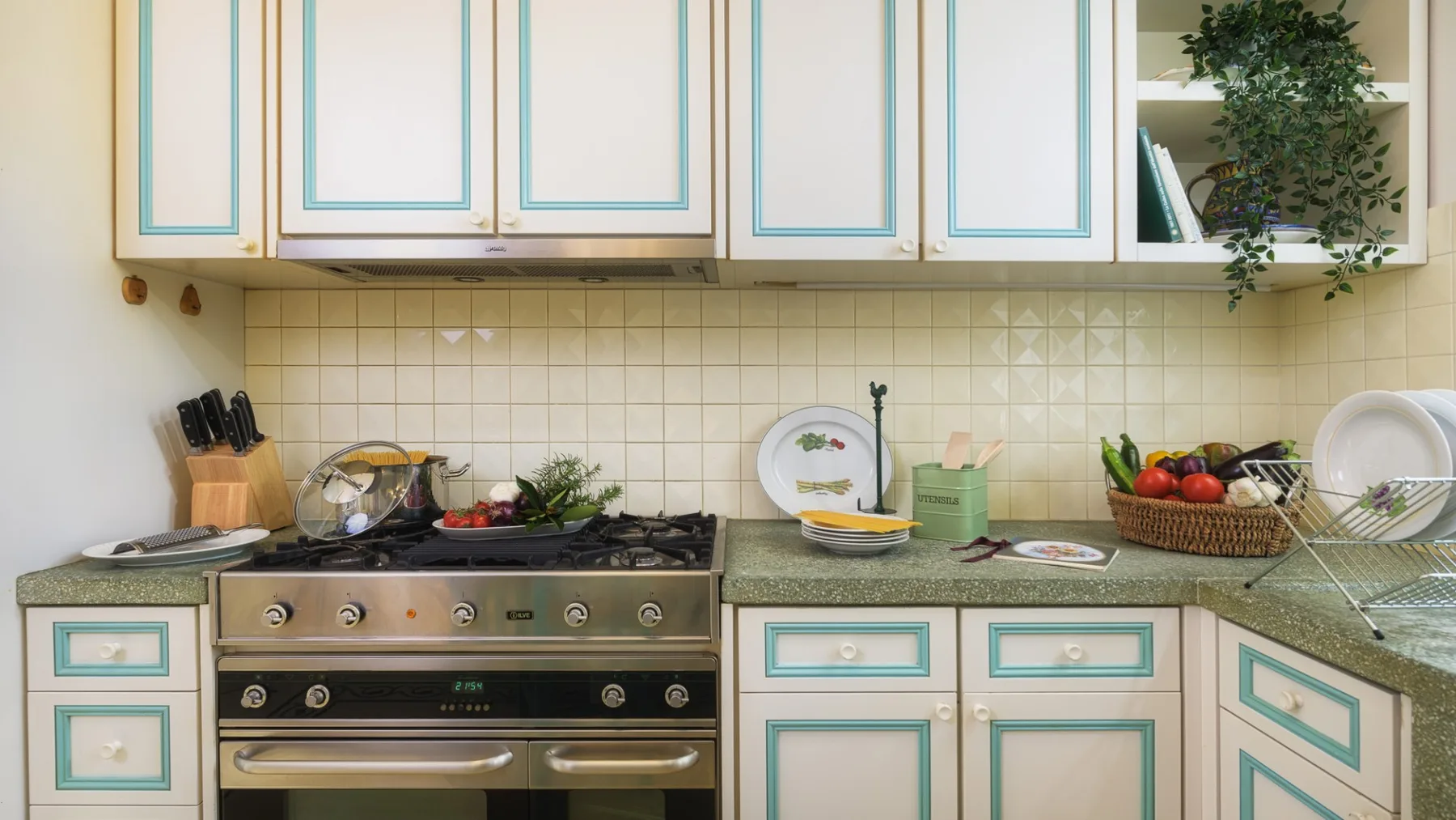 Una cocina con estufa, salpicadero de azulejos y gabinetes con bordes verdes.