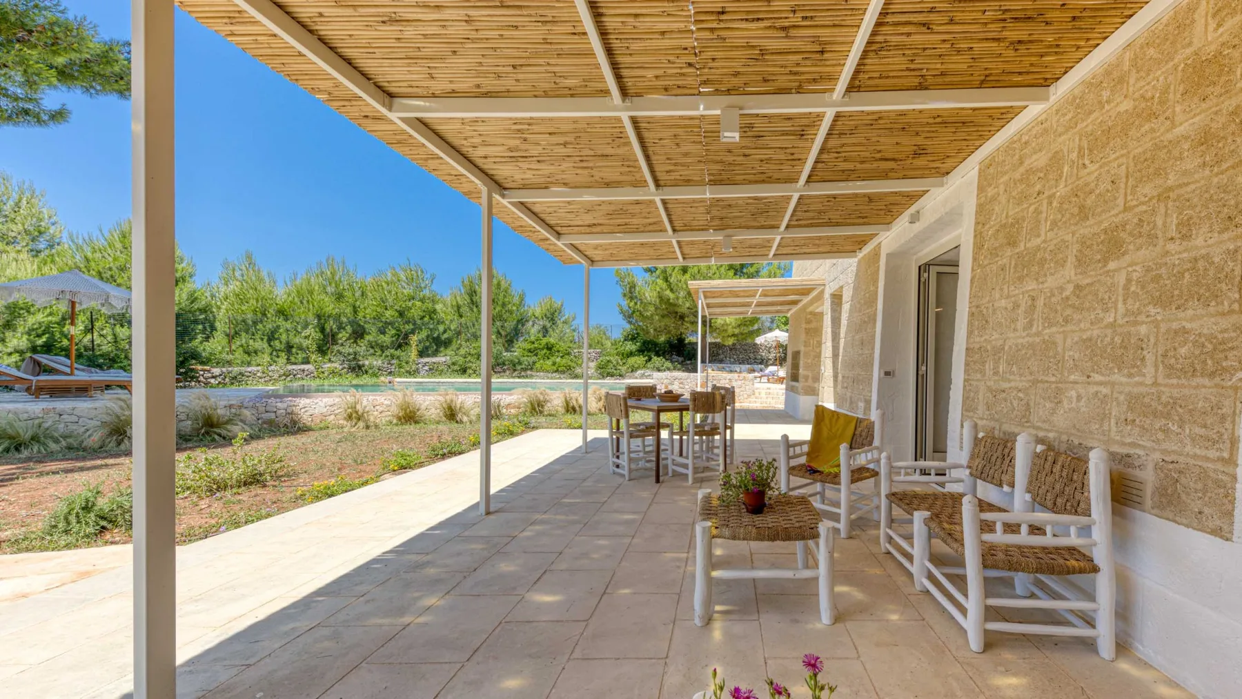 Un patio exterior cubierto con suelo de baldosas y asientos junto a un muro de piedra.