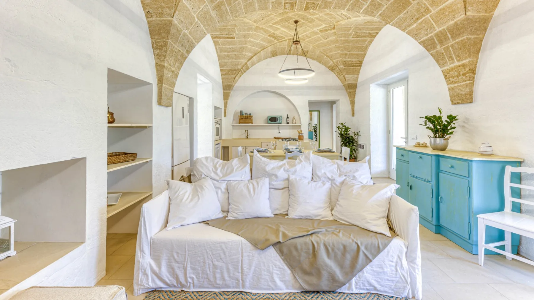Una sala luminosa con asientos blancos bajo un techo abovedado de piedra.