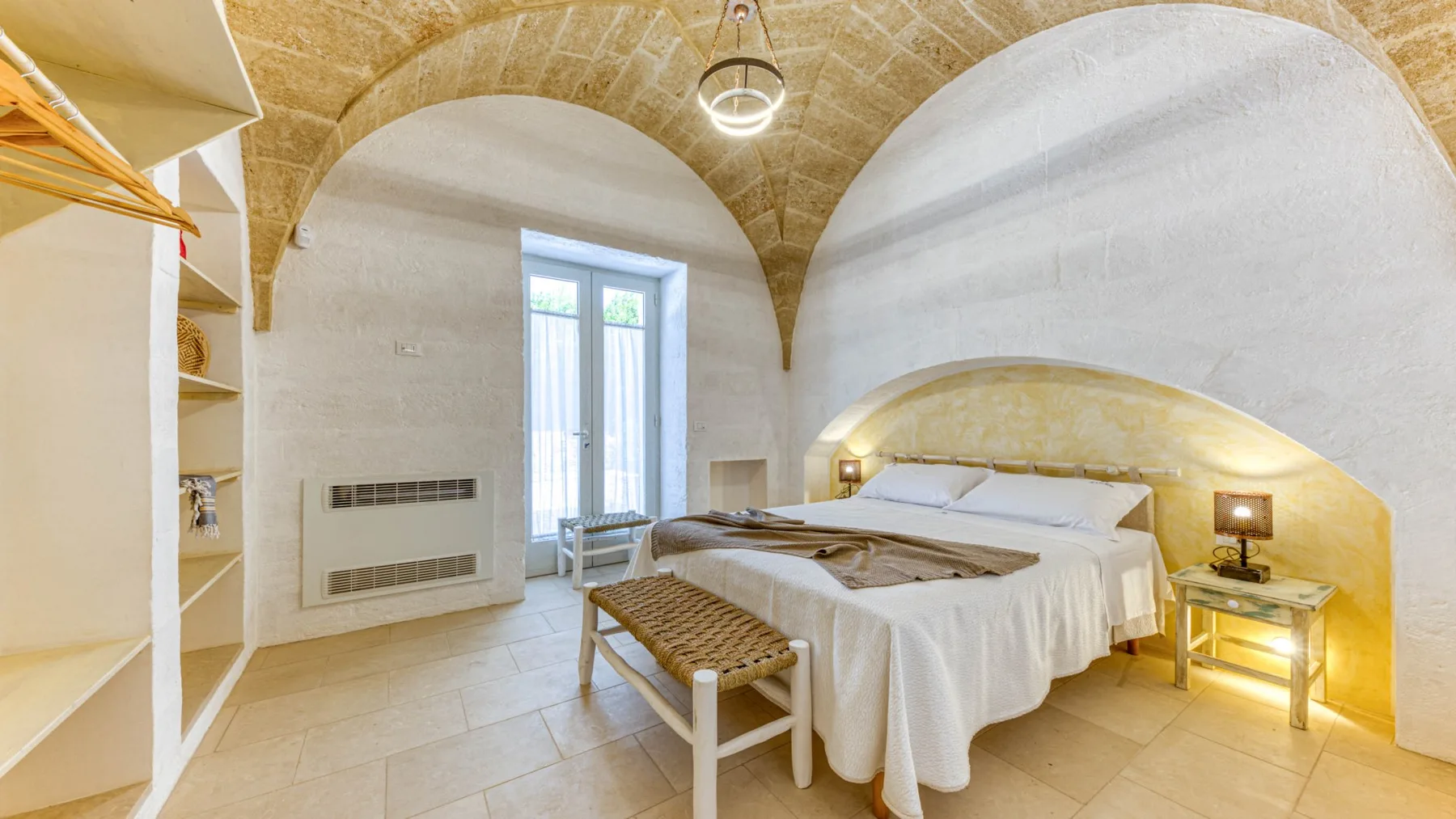 Un dormitorio con una cama, un banco y un alto techo abovedado.