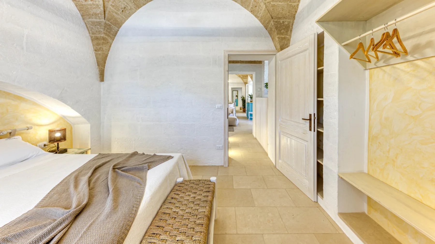 Un dormitorio con una cama junto a un armario abierto y una puerta.
