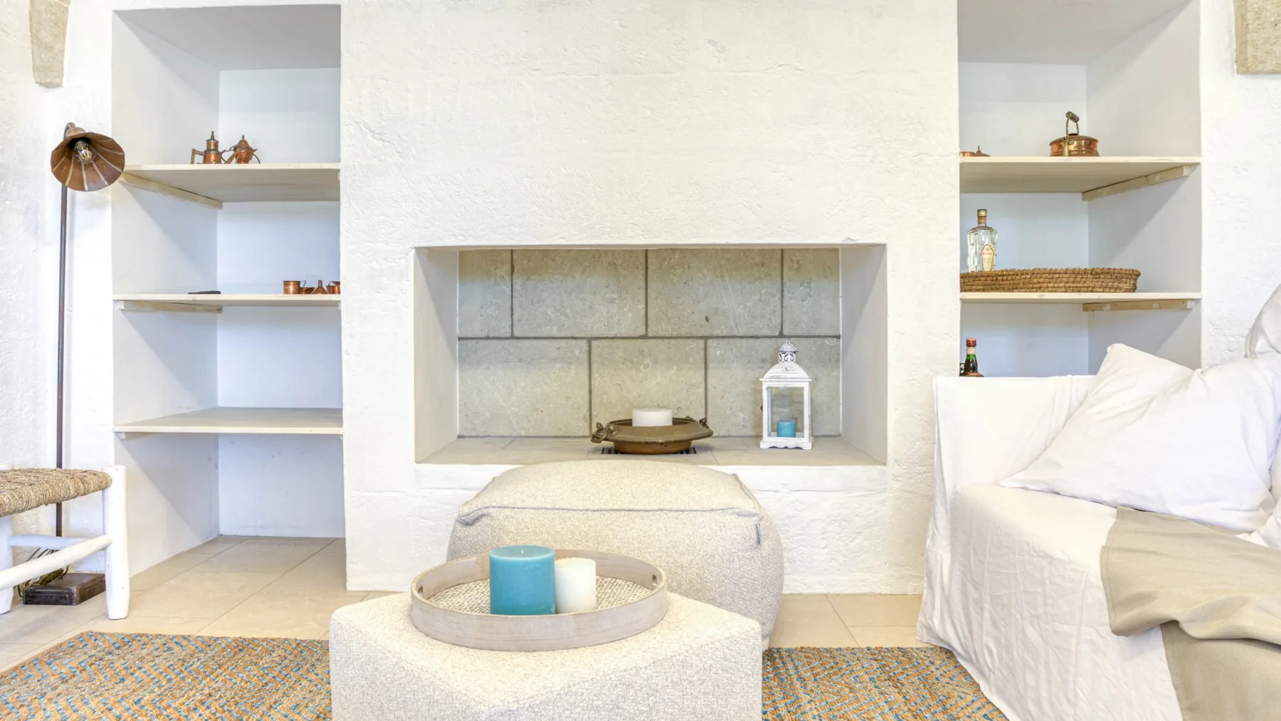 Una sala luminosa con estantes empotrados y una zona de asientos cubierta de blanco.