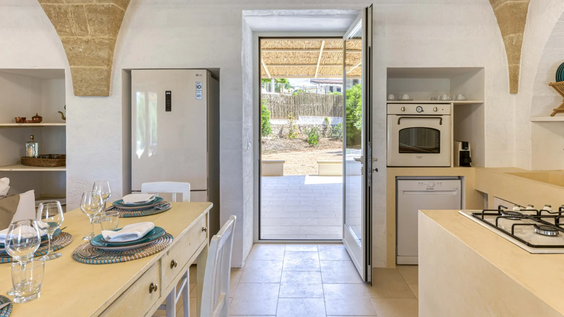 Una cocina luminosa con comedor se abre a un patio exterior por una puerta de vidrio.