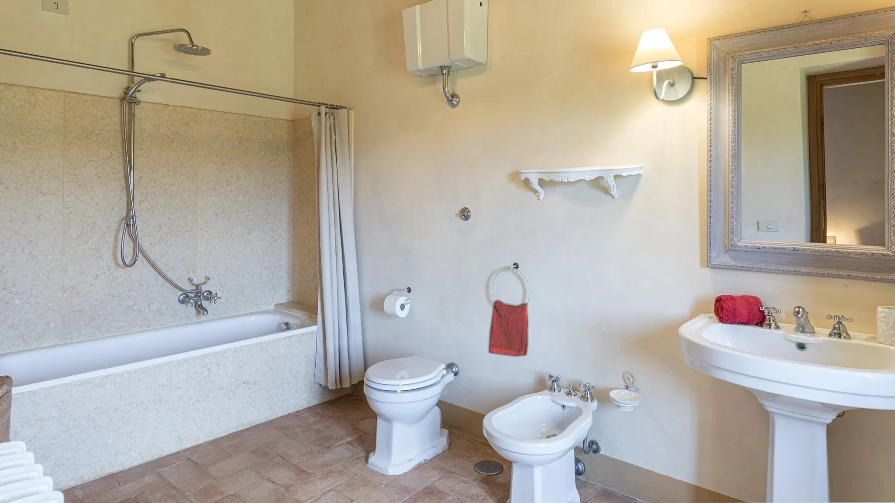 A bathroom with a bathtub, shower, toilet, bidet, and pedestal sink.