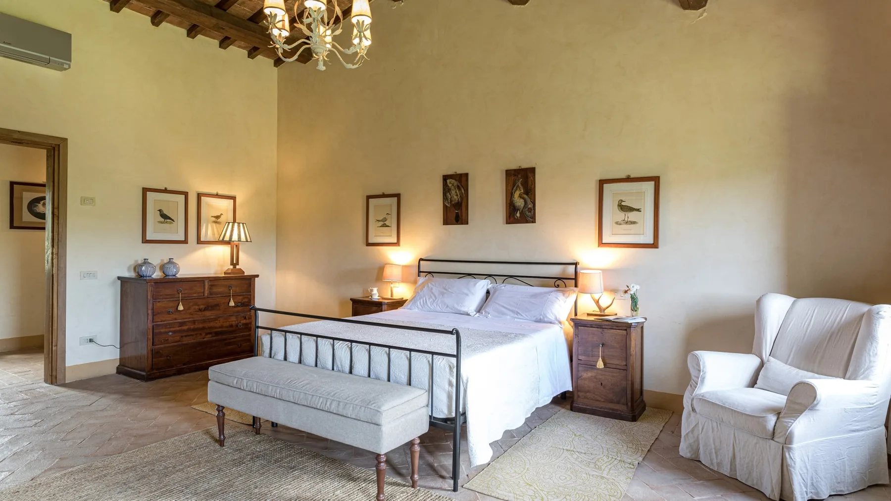A bedroom with a bed, bedside tables, and an upholstered bench.