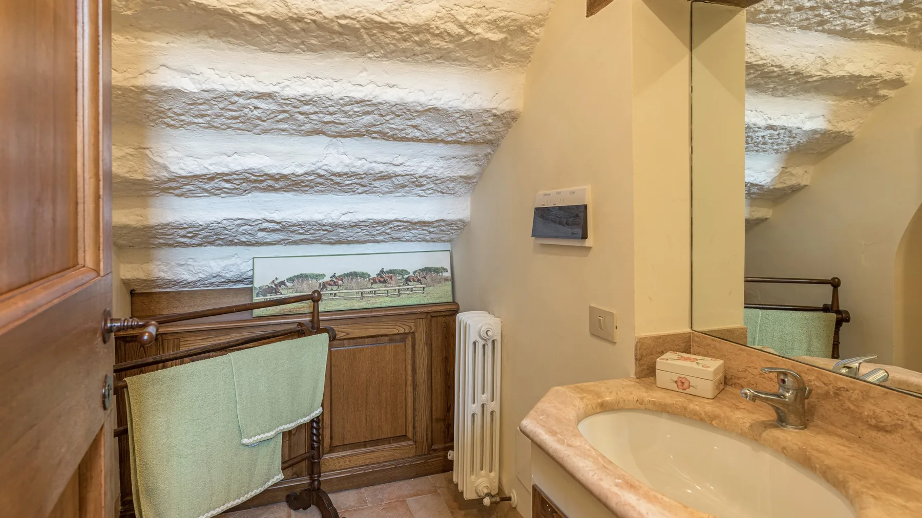 A bathroom vanity with a sink stands beside a window with a textured shade.