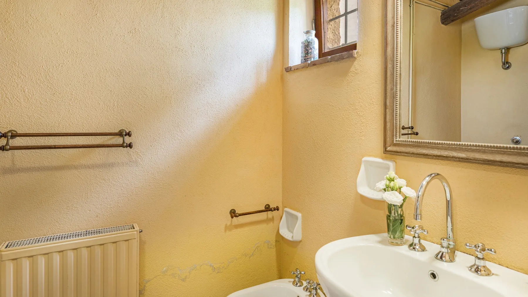 A bathroom with a sink, wall mirror, and radiator.