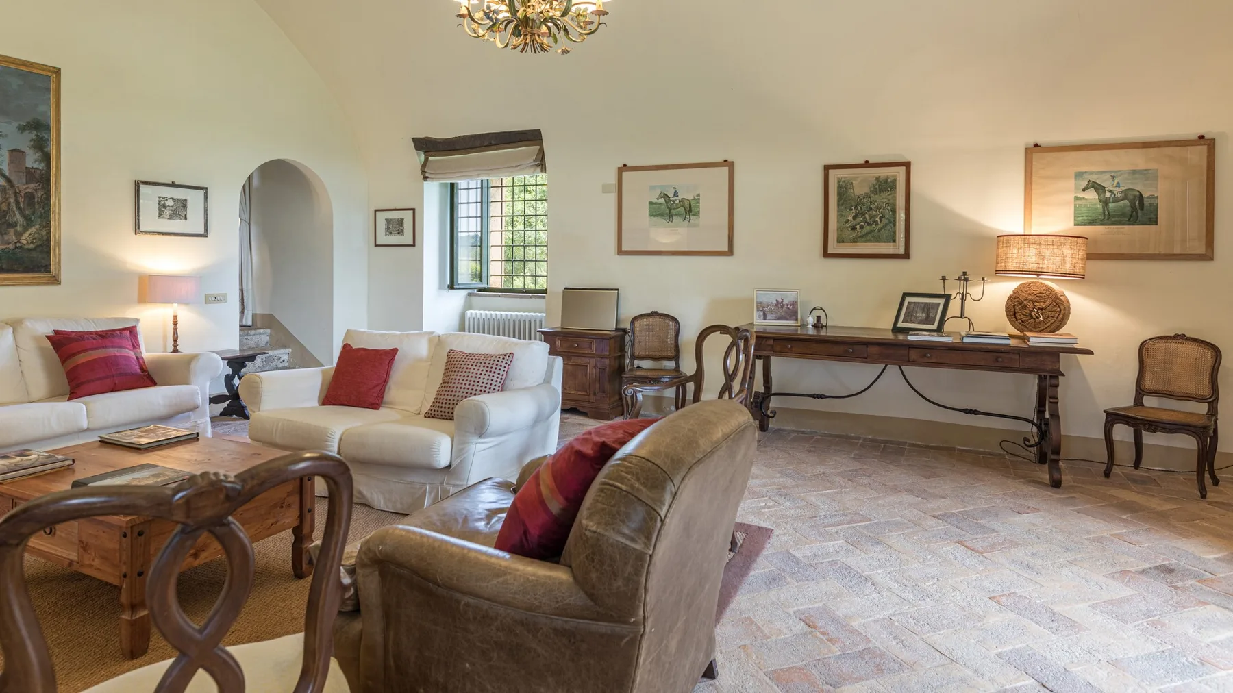 A living room with seating, framed artwork, and a long wooden table.