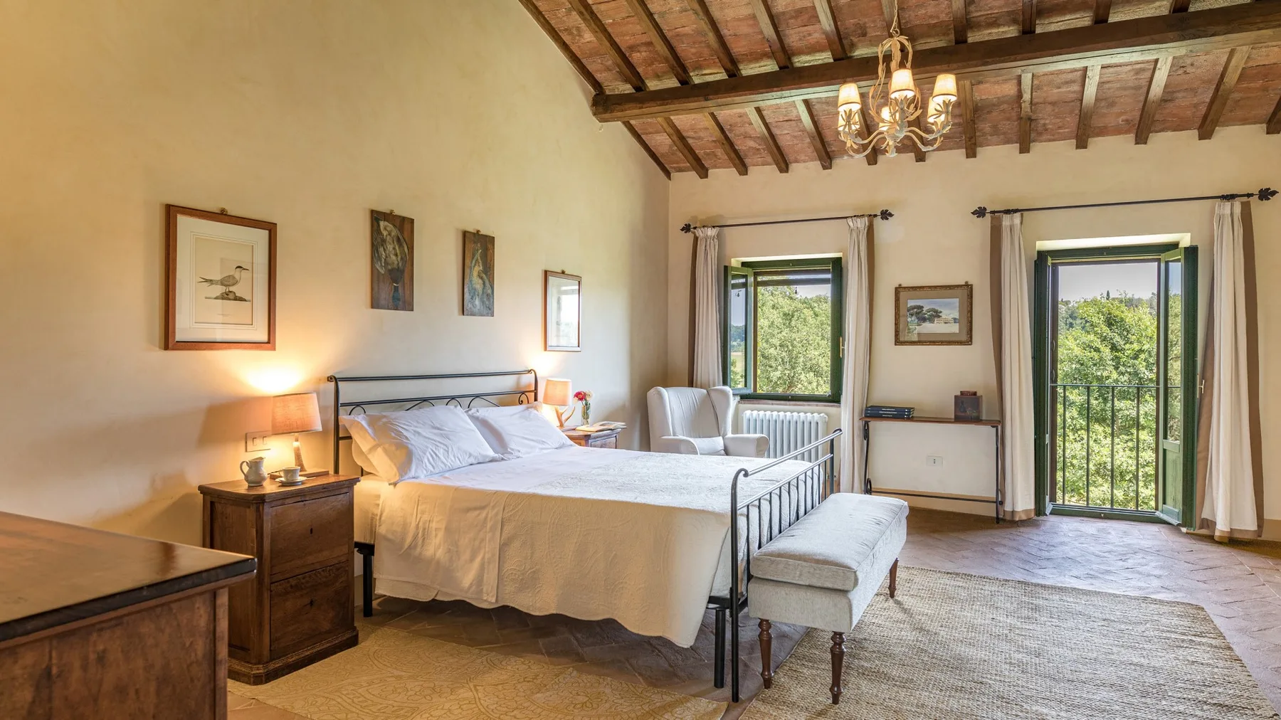 A bedroom with a large bed, exposed wooden ceiling beams, and garden views.