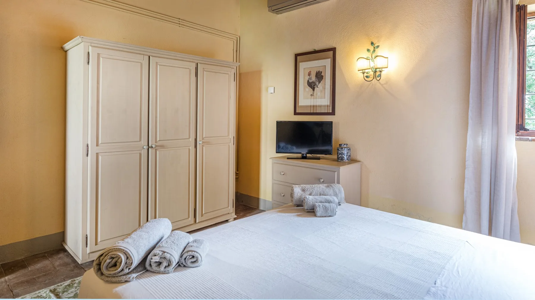A bedroom with a bed, towels, and a wardrobe.