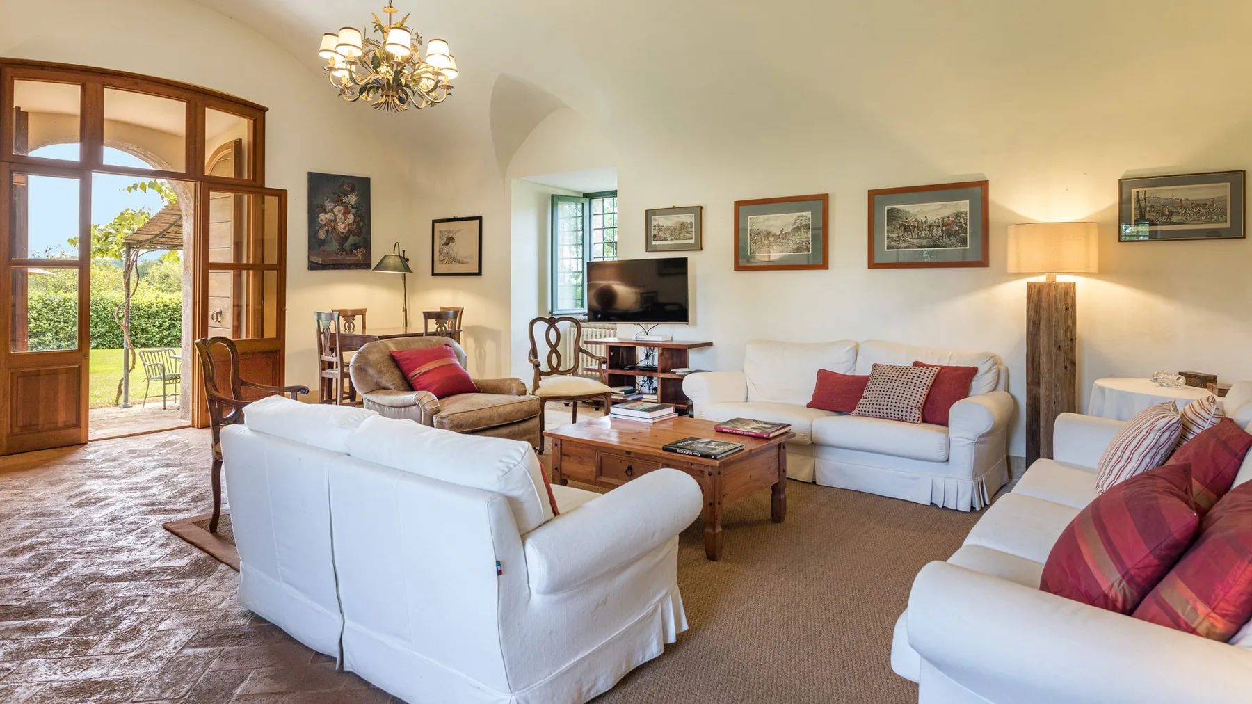 A bright living room with white seating, a wooden coffee table, and large glass doors.