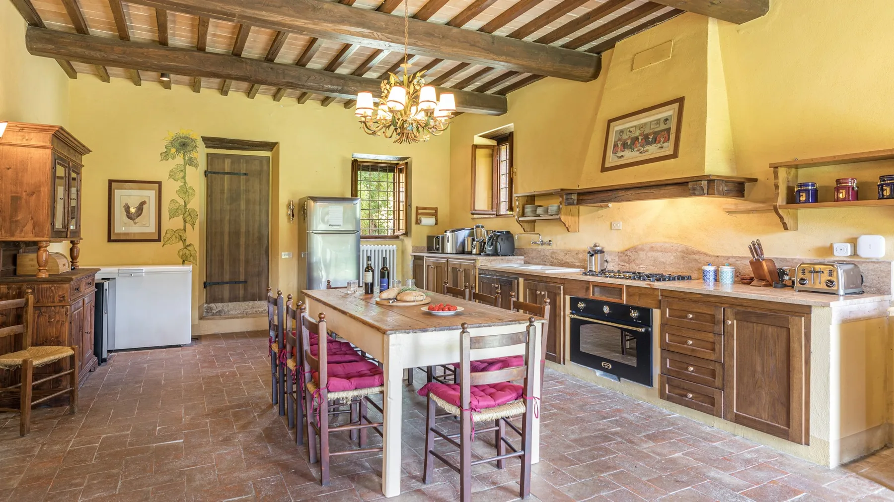 A spacious kitchen with a central island, wooden cabinets, and exposed ceiling beams.