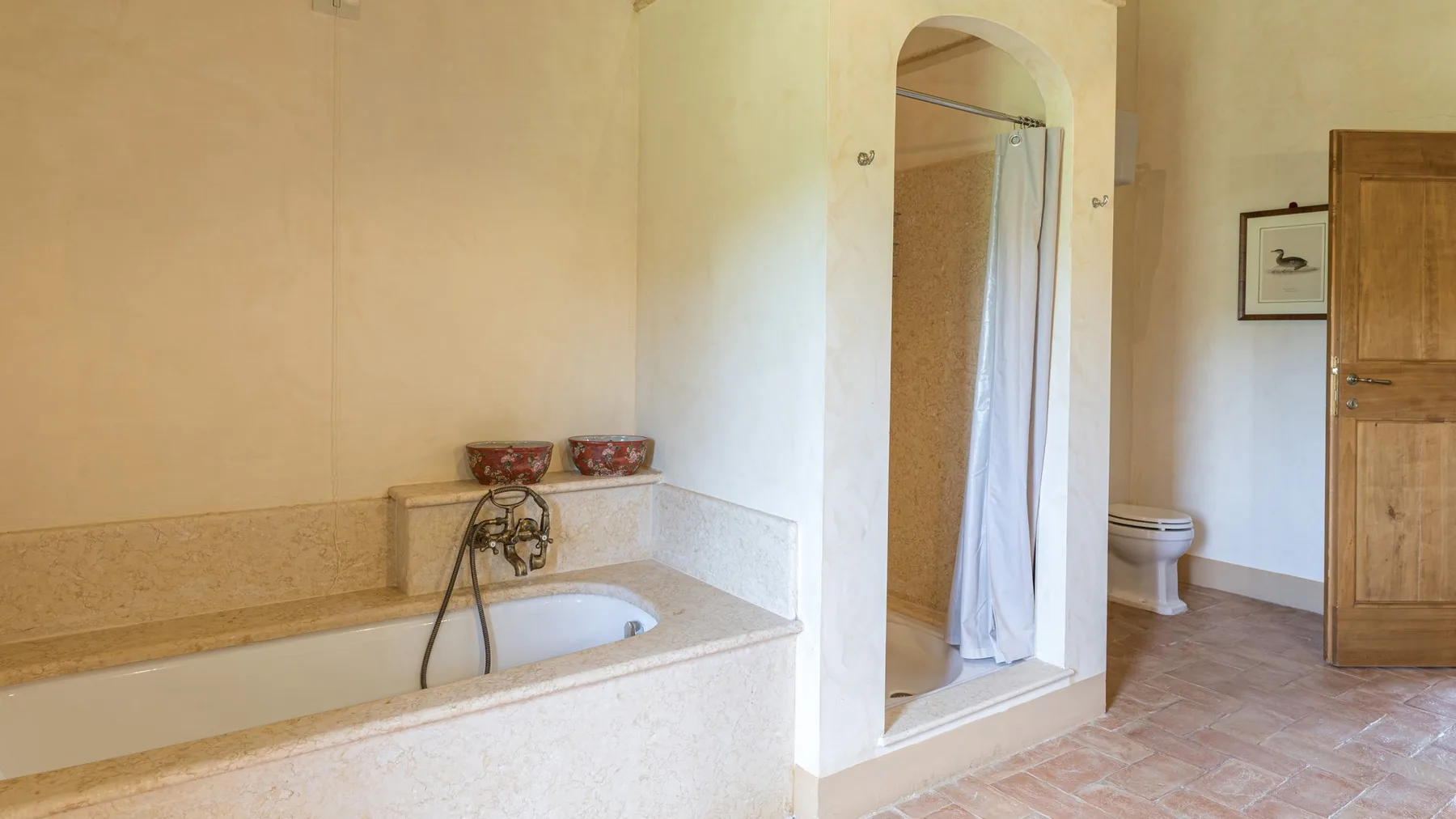 A bathroom with a bathtub and a curtained shower alcove.