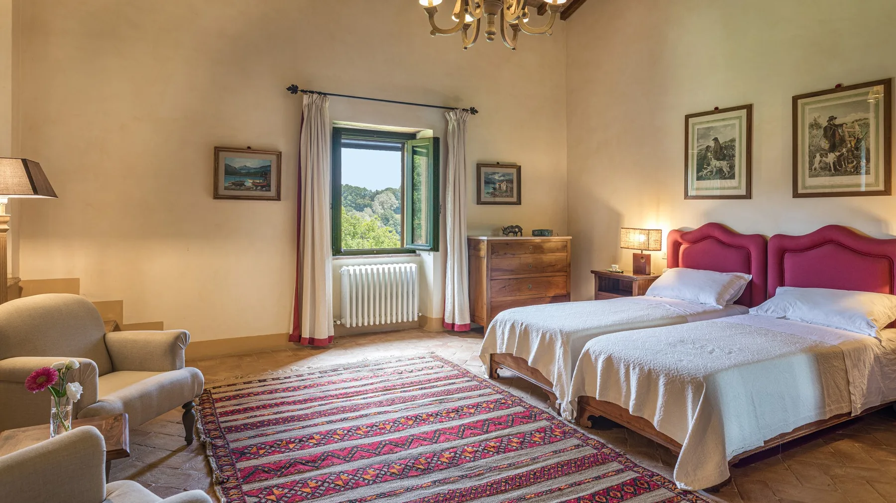 A bedroom with two beds, a window, and a patterned rug.