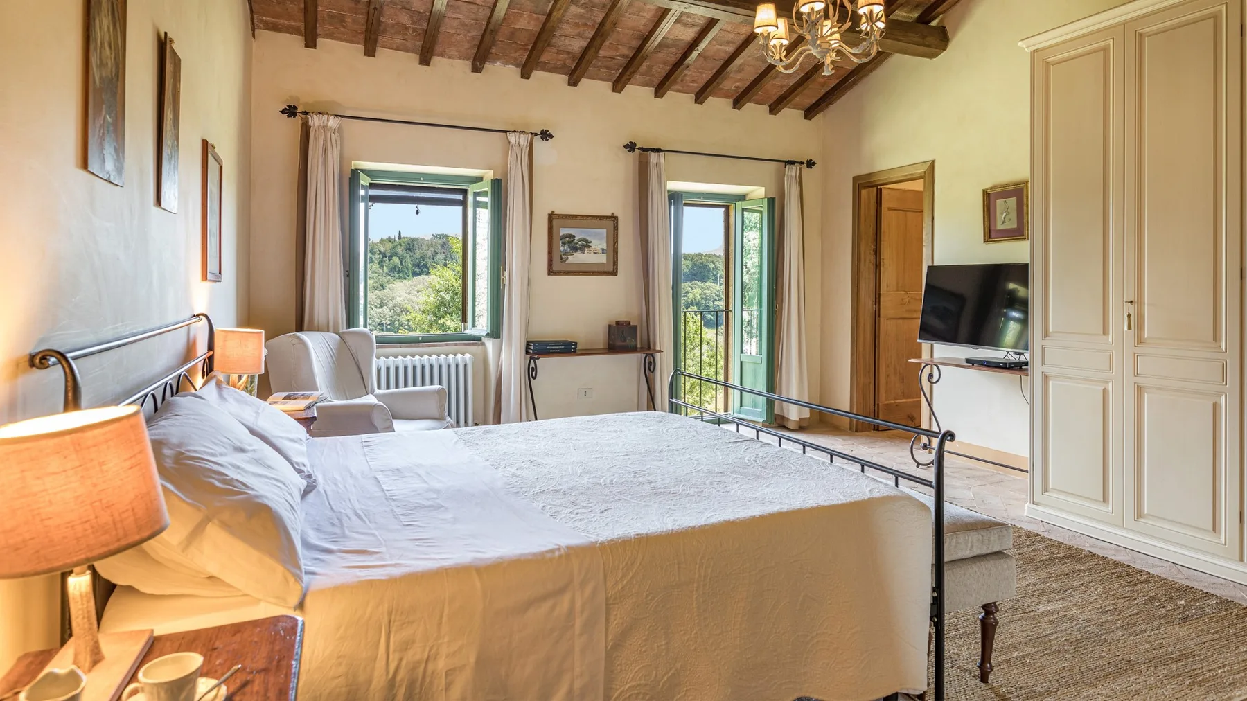 A bedroom with a bed, two windows, and exposed wooden ceiling beams.