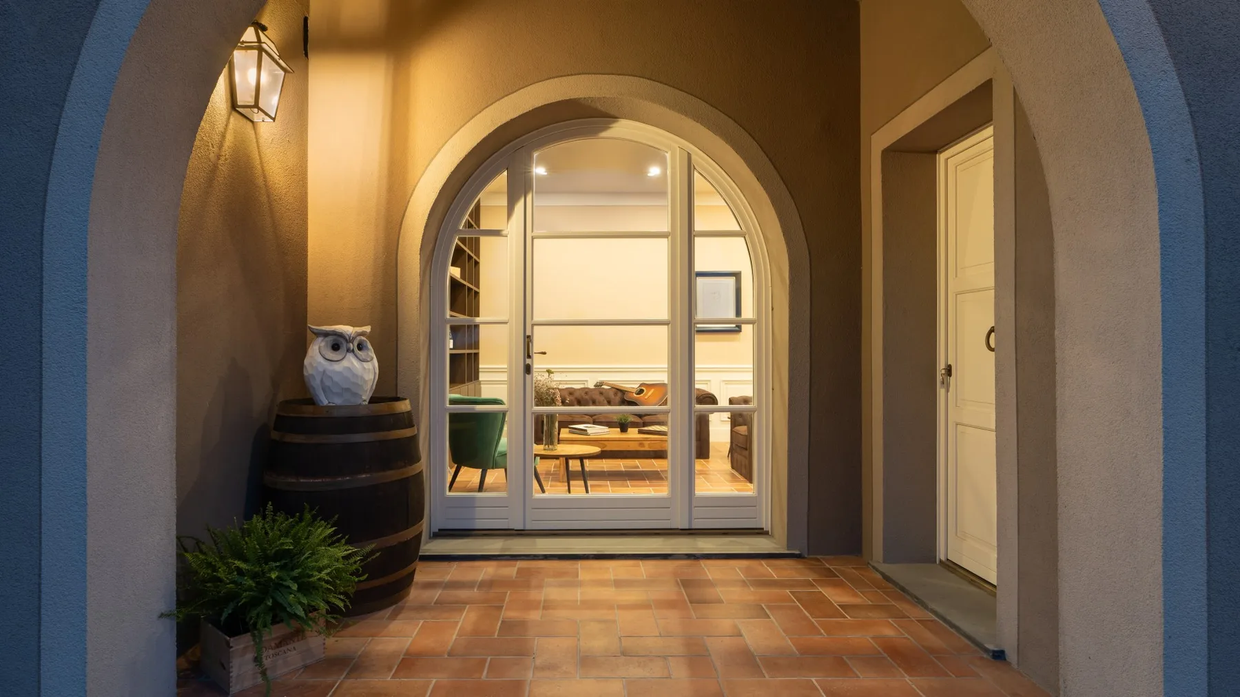 Una entrada con arco se abre a una habitación luminosa, con baldosas de tono terracota.